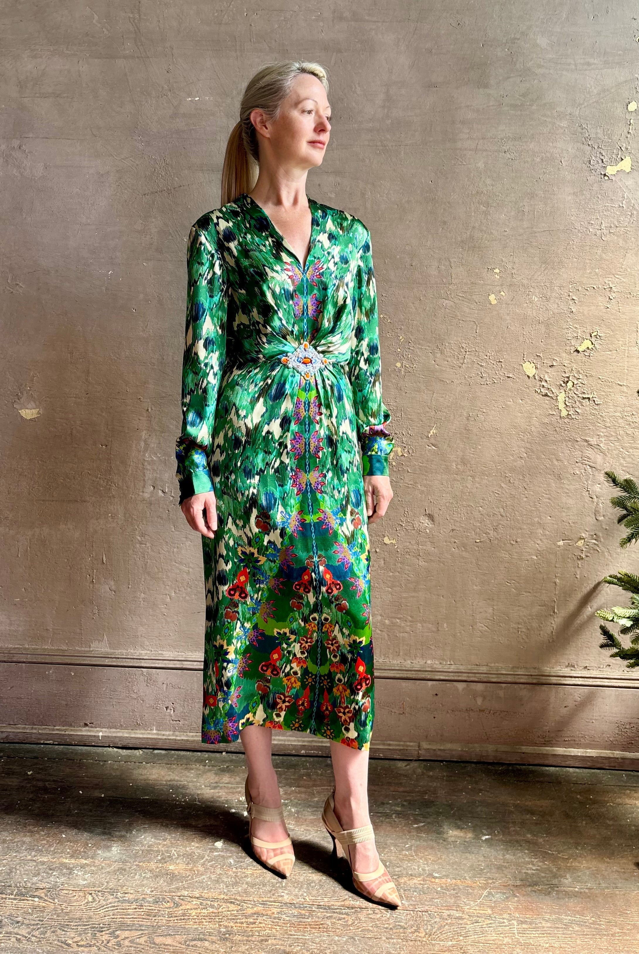 Mature woman wearing Saloni Mya silk long sleeve green floral midi dress with broach gathered waist V-neck