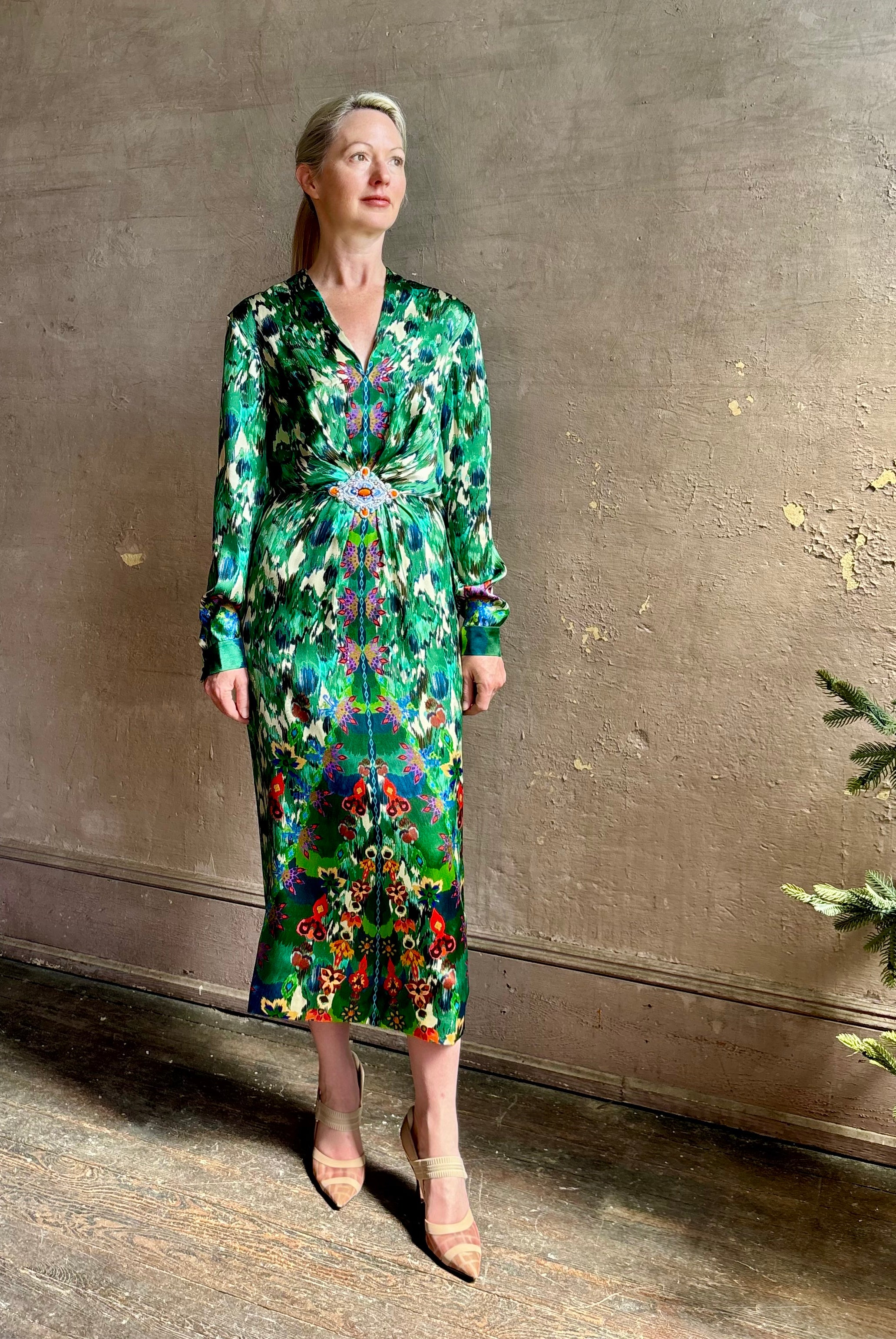 Mature woman wearing Saloni Mya silk long sleeve green floral midi dress with broach gathered waist V-neck