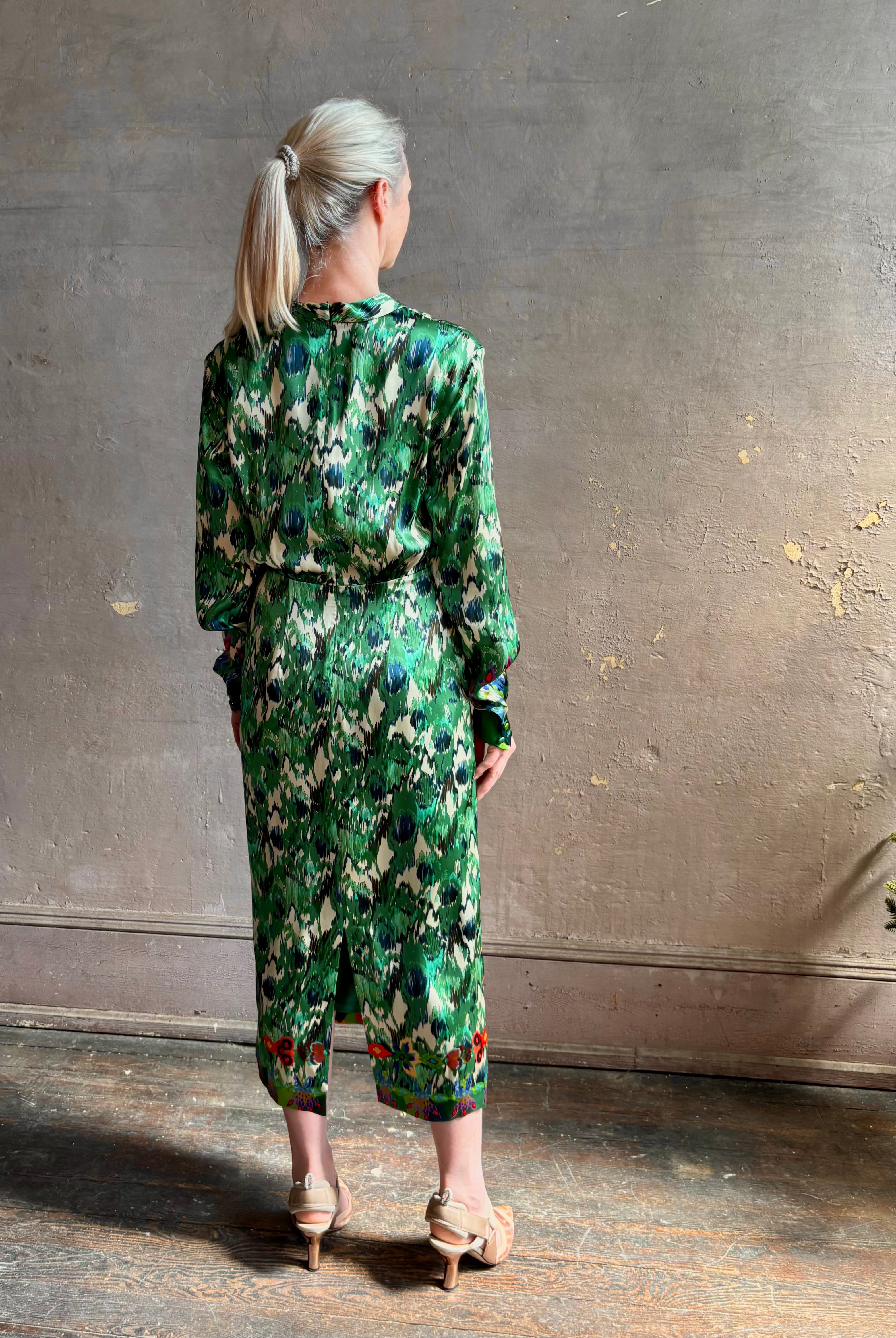 Mature woman wearing Saloni Mya silk long sleeve green floral midi dress with broach gathered waist V-neck