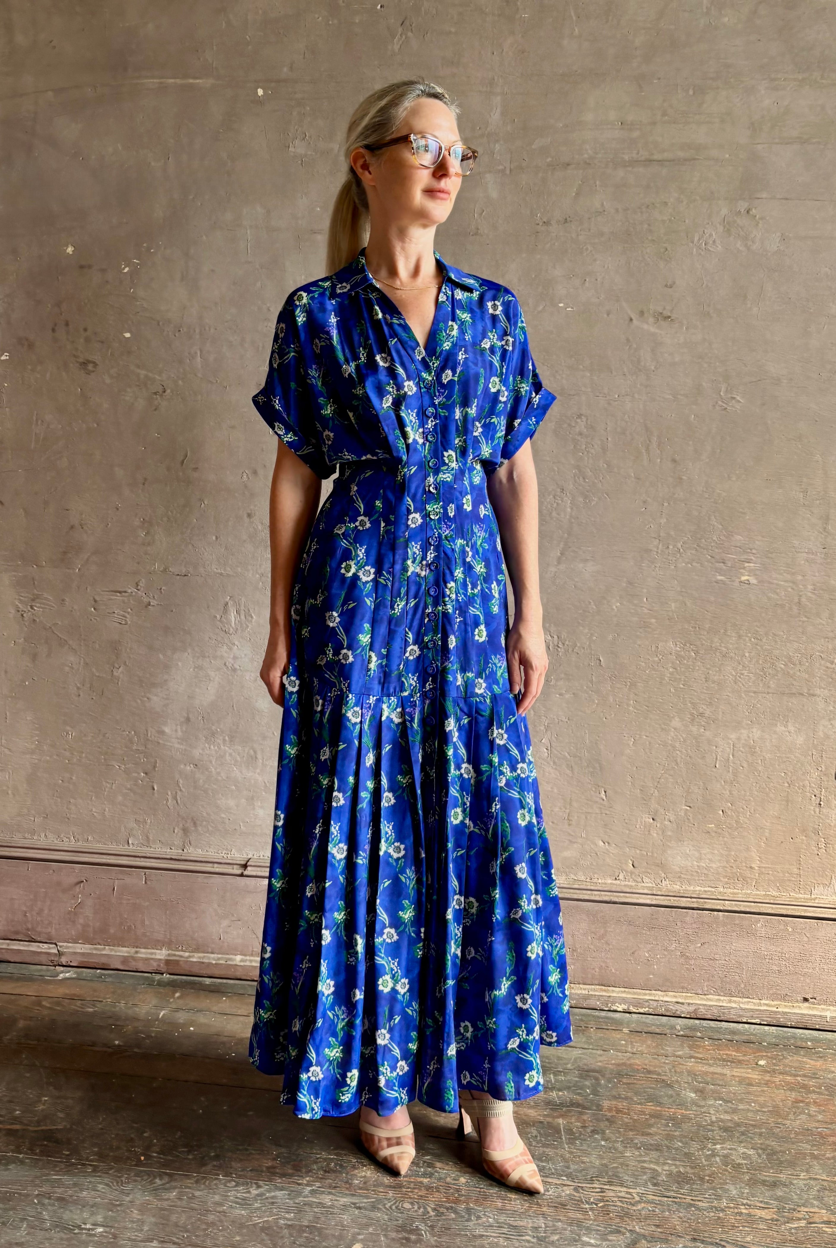 Woman wearing Saloni silk maxi Riya dress with short sleeves bouson top drop waist v-neck button front cobalt