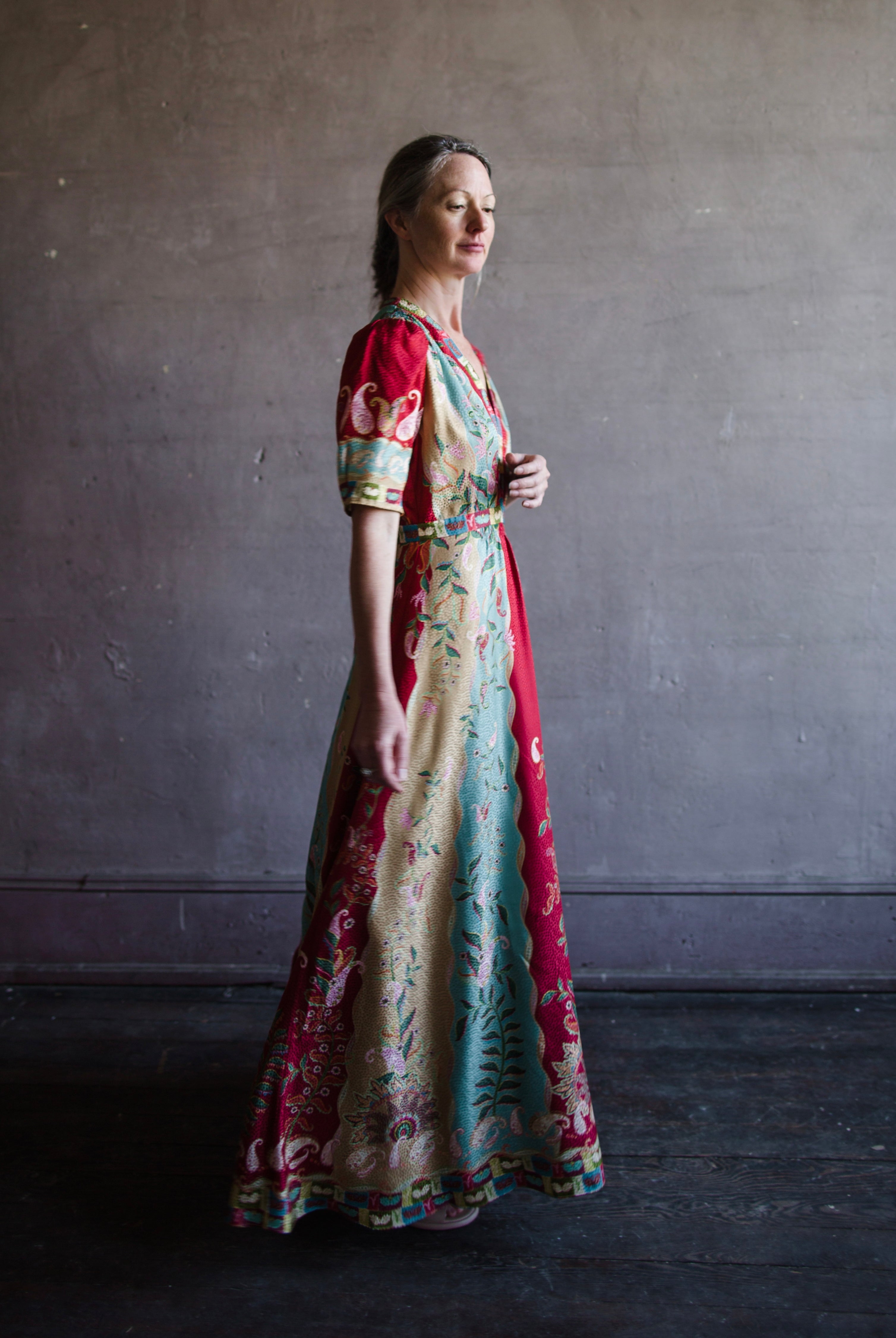 Mature woman wearing Saloni Tabitha silk maxi dress v-neck short sleeves empire waist red yellow aqua floral