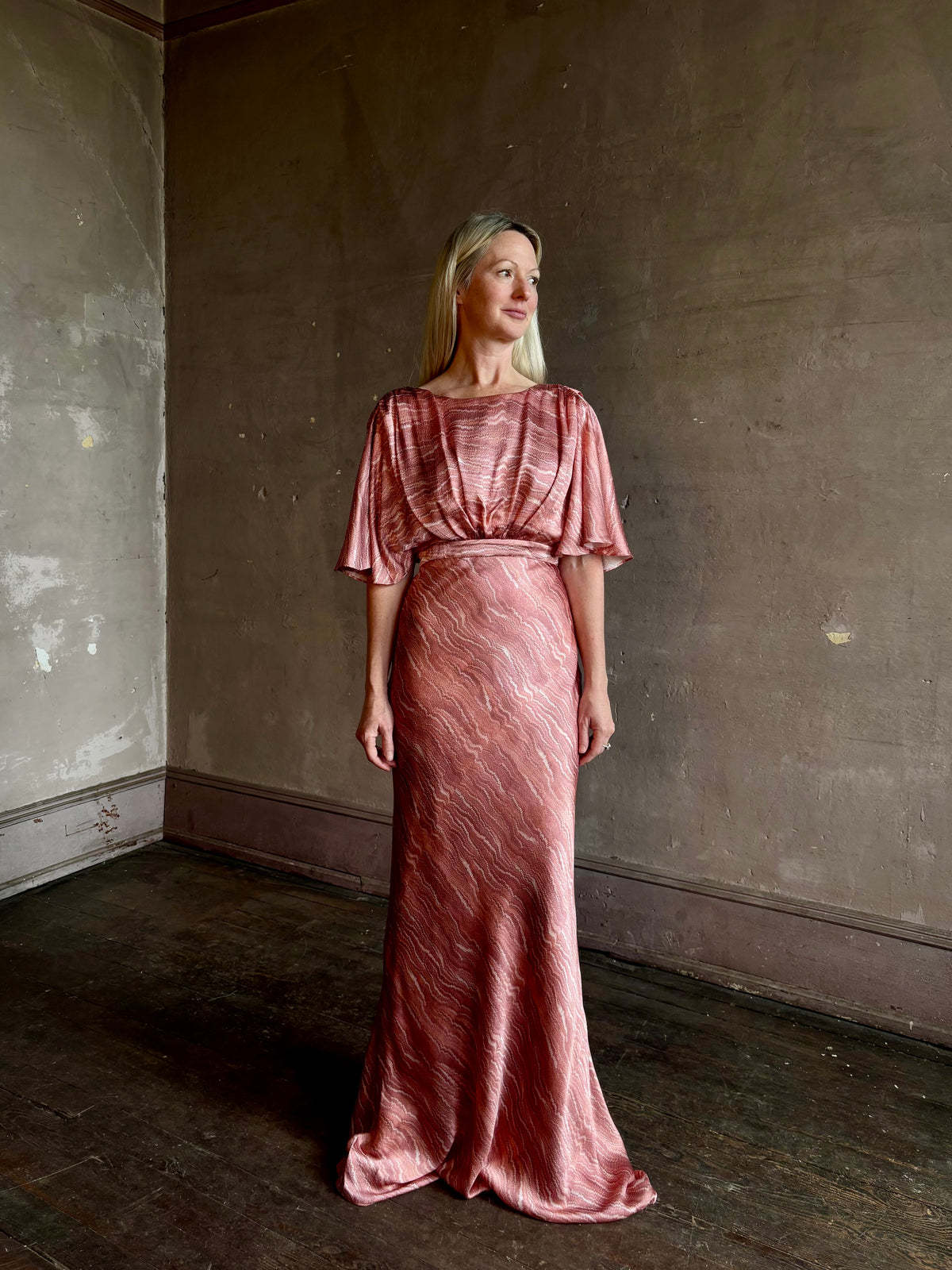 Mature woman wearing Saloni silk Winona Dress in Blush Marbling print V-back detail short sleeves empire waist Romantic occasion gown