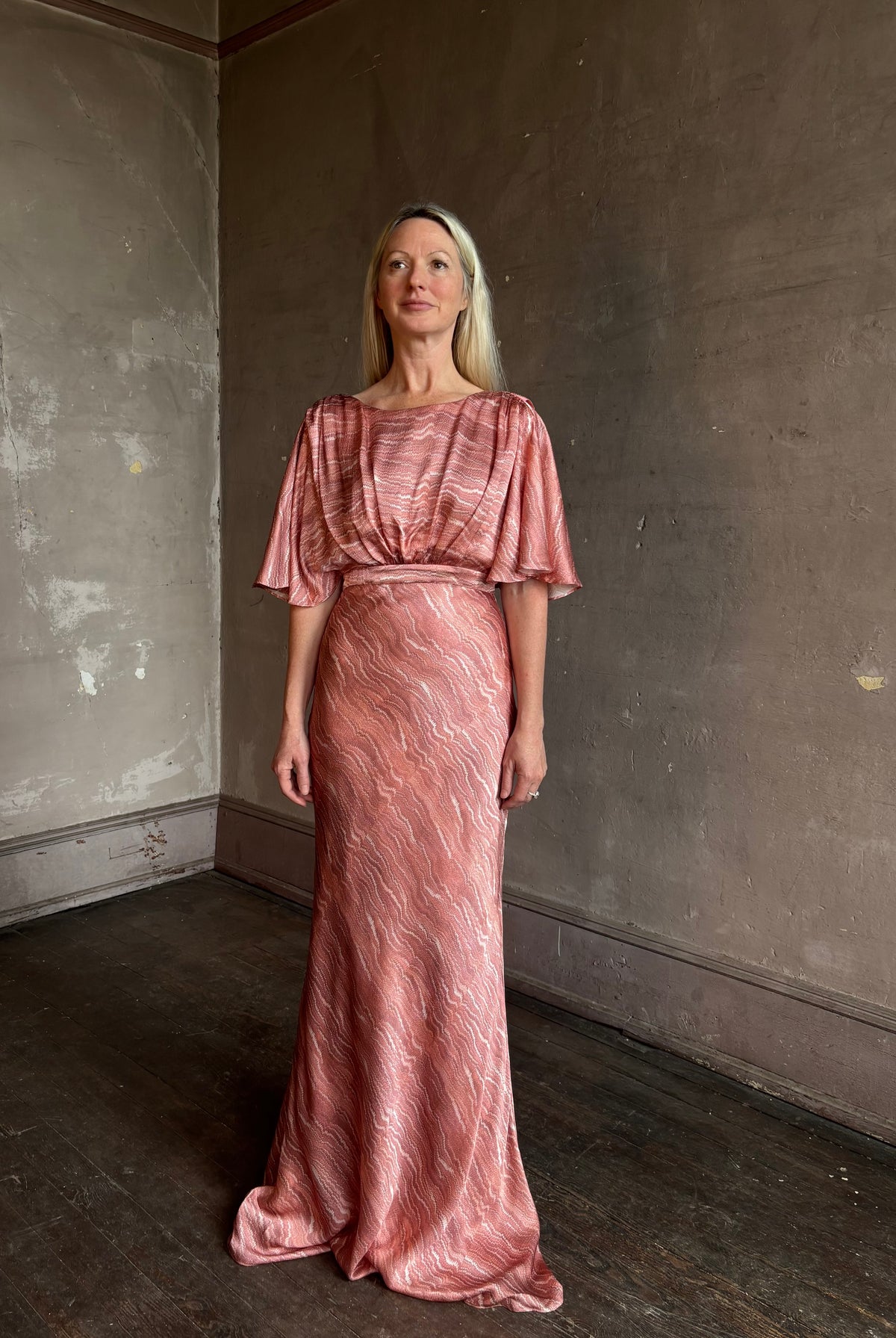 Mature woman wearing Saloni silk Winona Dress in Blush Marbling print V-back detail short sleeves empire waist Romantic occasion gown