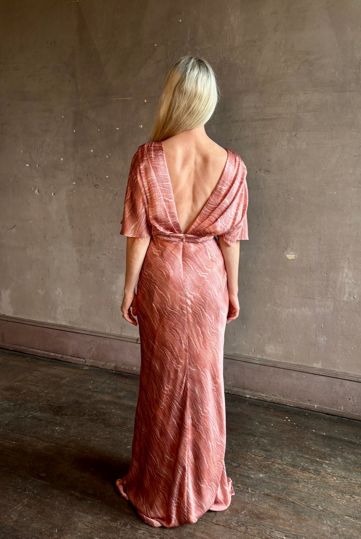 Mature woman wearing a pink long gown with a deep V-back and short sleeves Saloni Winona silk dress