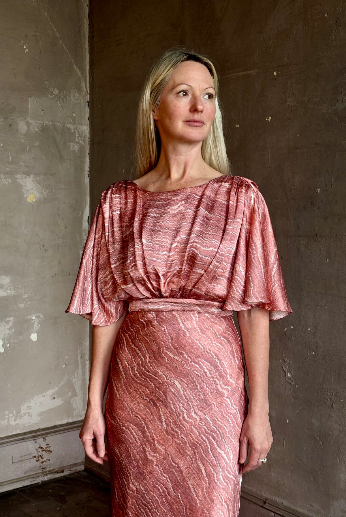 Mature woman wearing Saloni silk Winona Dress in Blush Marbling print V-back detail short sleeves empire waist Romantic occasion gown