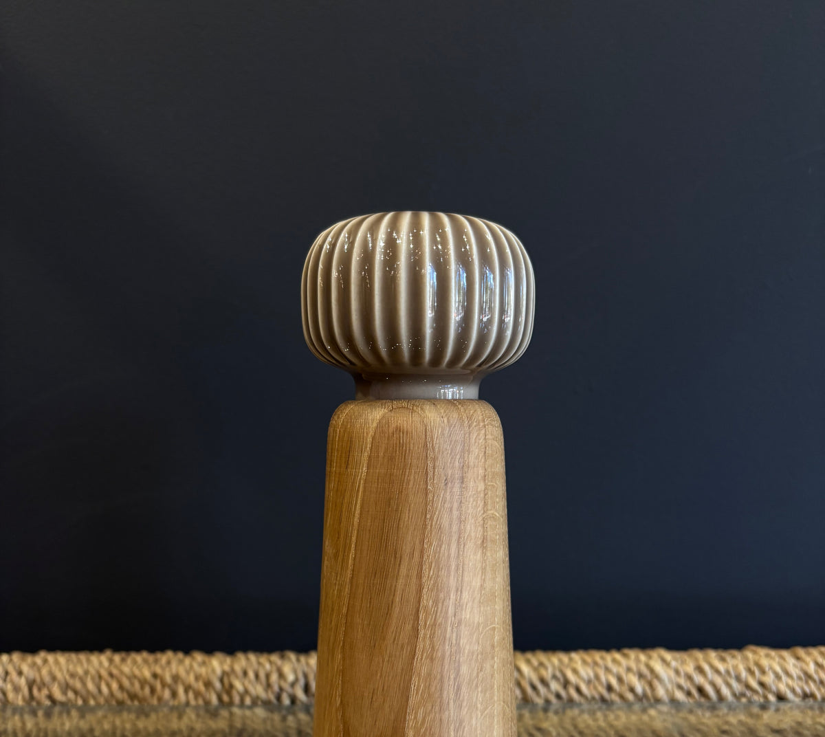 A wooden spice grinder with a neutral taupe beige ribbed ceramic top and a natural finish oak wood body
