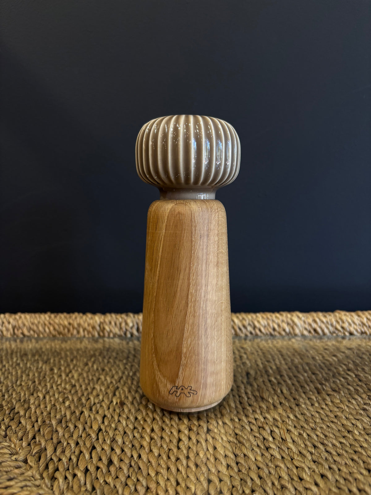 A wooden spice grinder with a neutral taupe beige ribbed ceramic top and a natural finish oak wood body