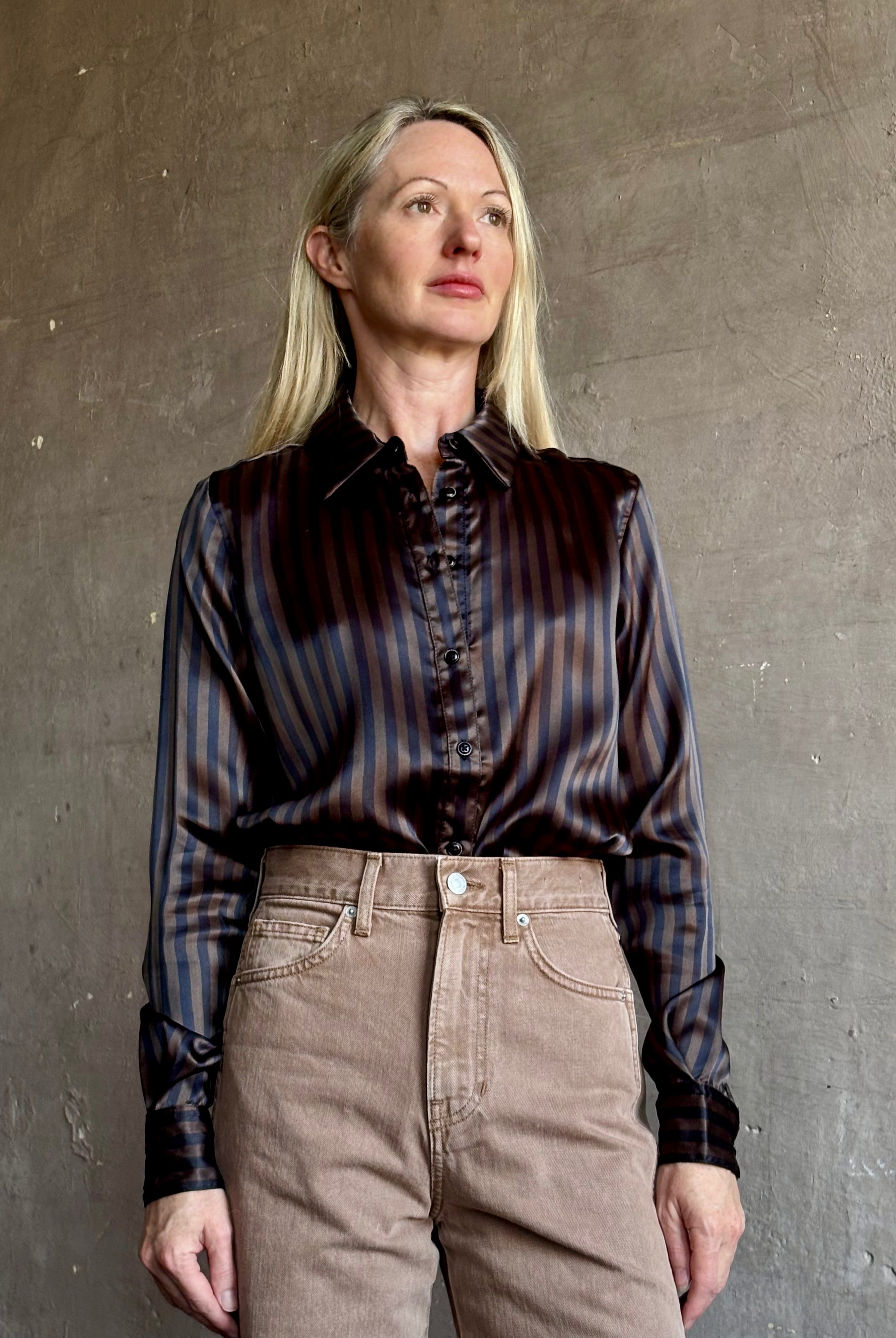 Image of woman wearing luxury brand SPRWMN Fonda silk button up shirt in a black and brown stripe modern classic.