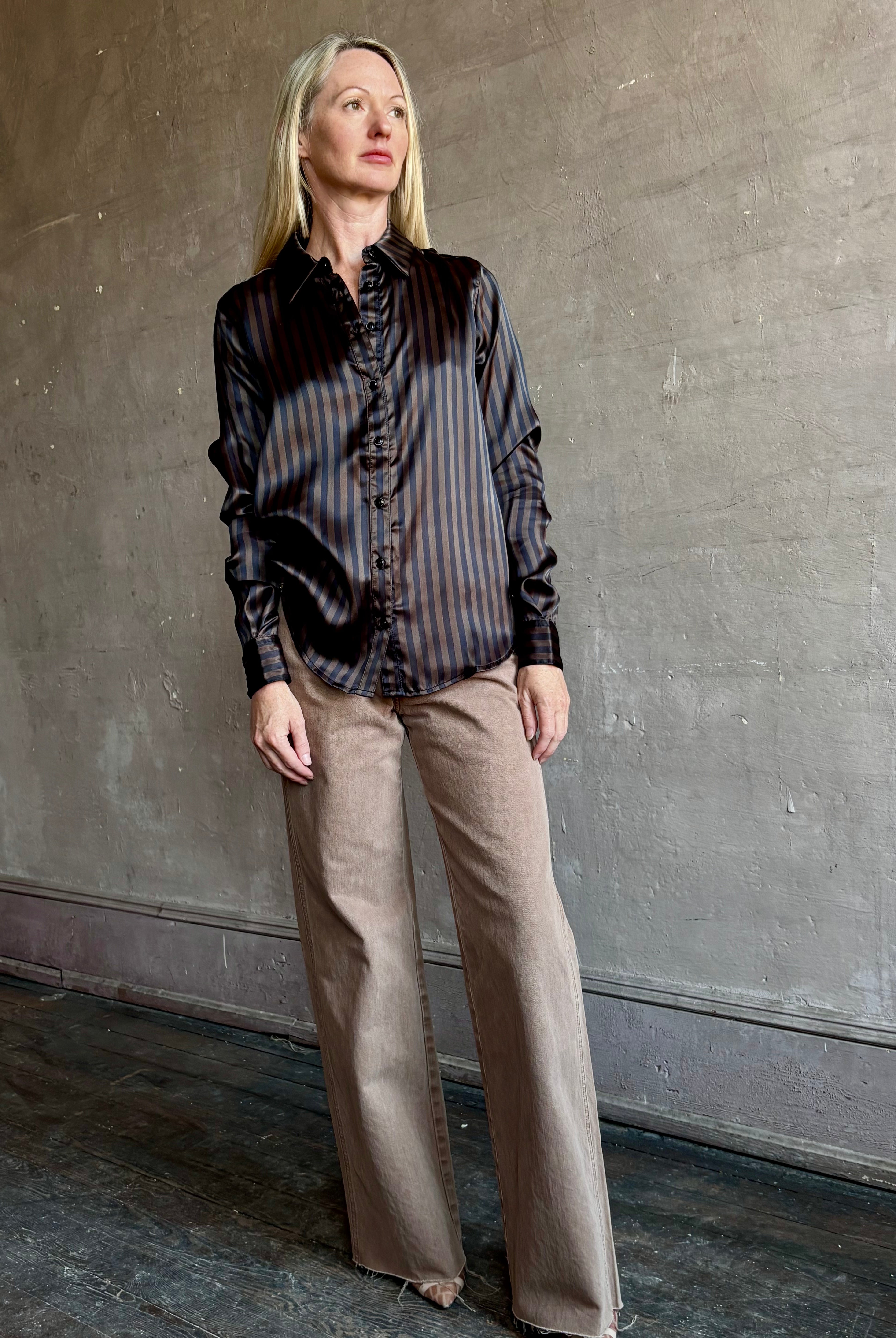 Image of woman wearing luxury brand SPRWMN Fonda silk button up shirt in a black and brown stripe modern classic.