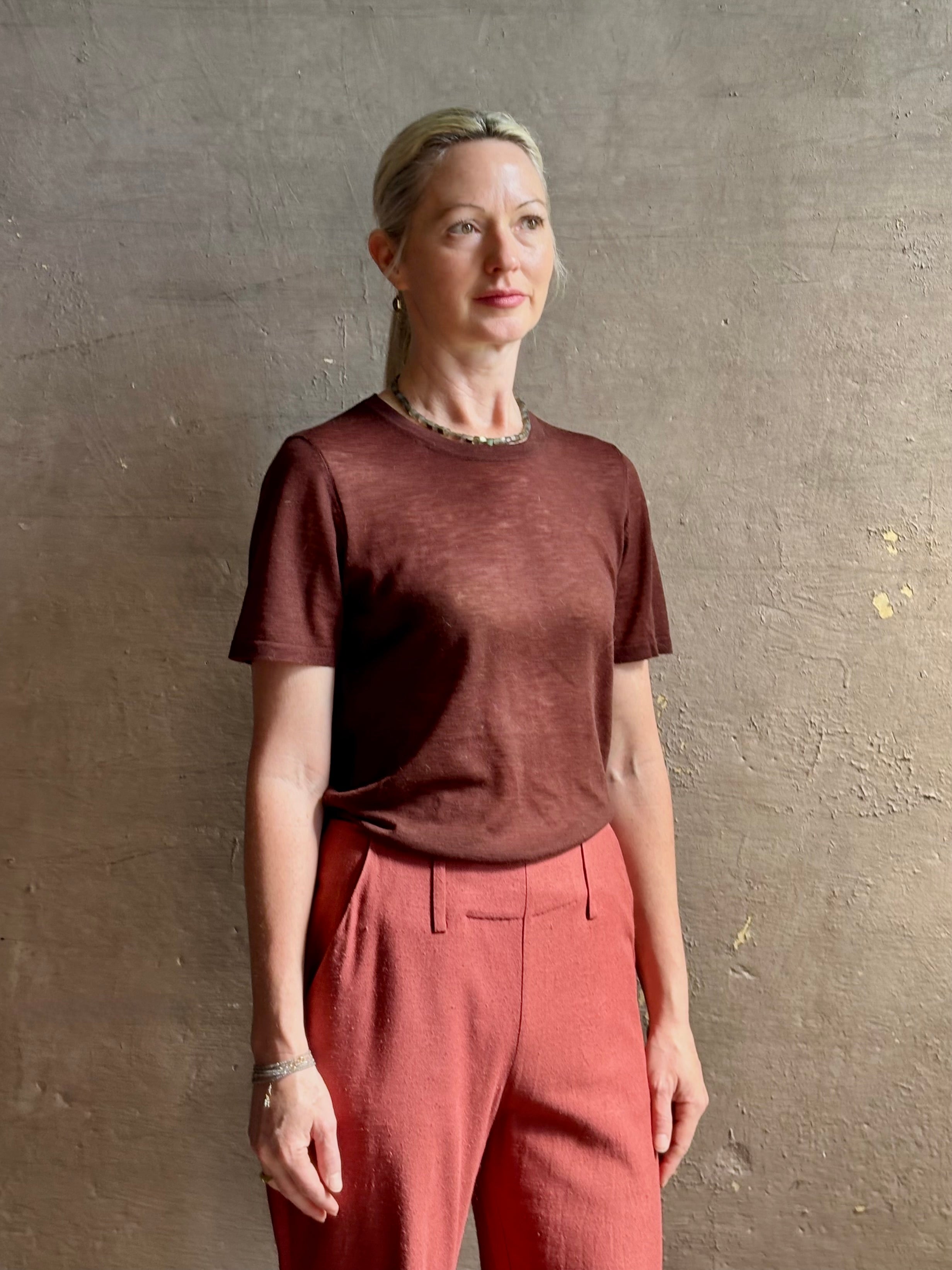 Mature woman wearing premium polished layer SPRWMN classic brown wool tee shirt with crew neck and short sleeves and very light weight for a summer elevated basic or cool weather layering