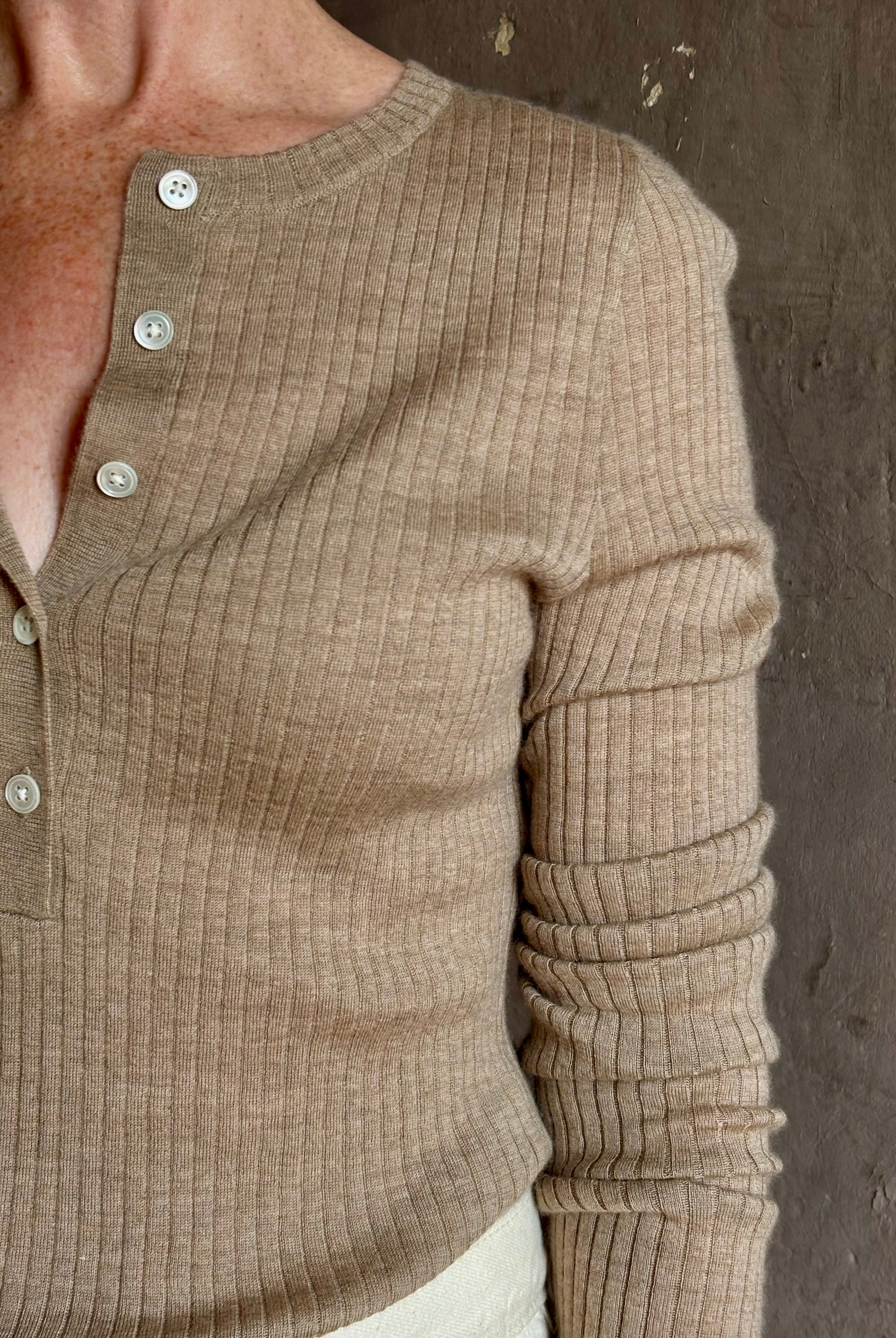 Mature woman wearing SPRWMN beige ribbed round neck cashmere henley top with long sleeves elevated casual wear