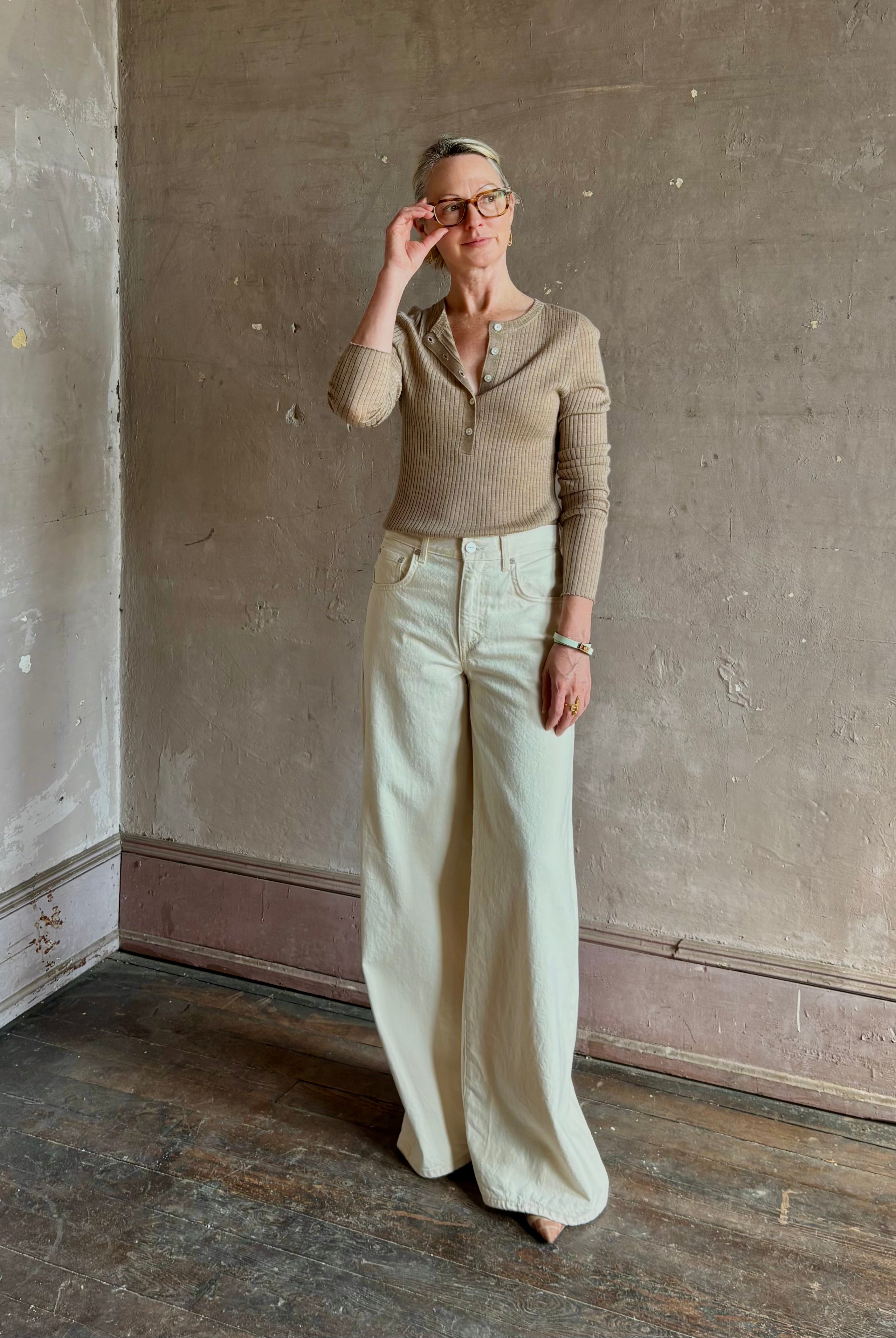 Mature woman wearing SPRWMN beige ribbed round neck cashmere henley top with long sleeves elevated casual wear