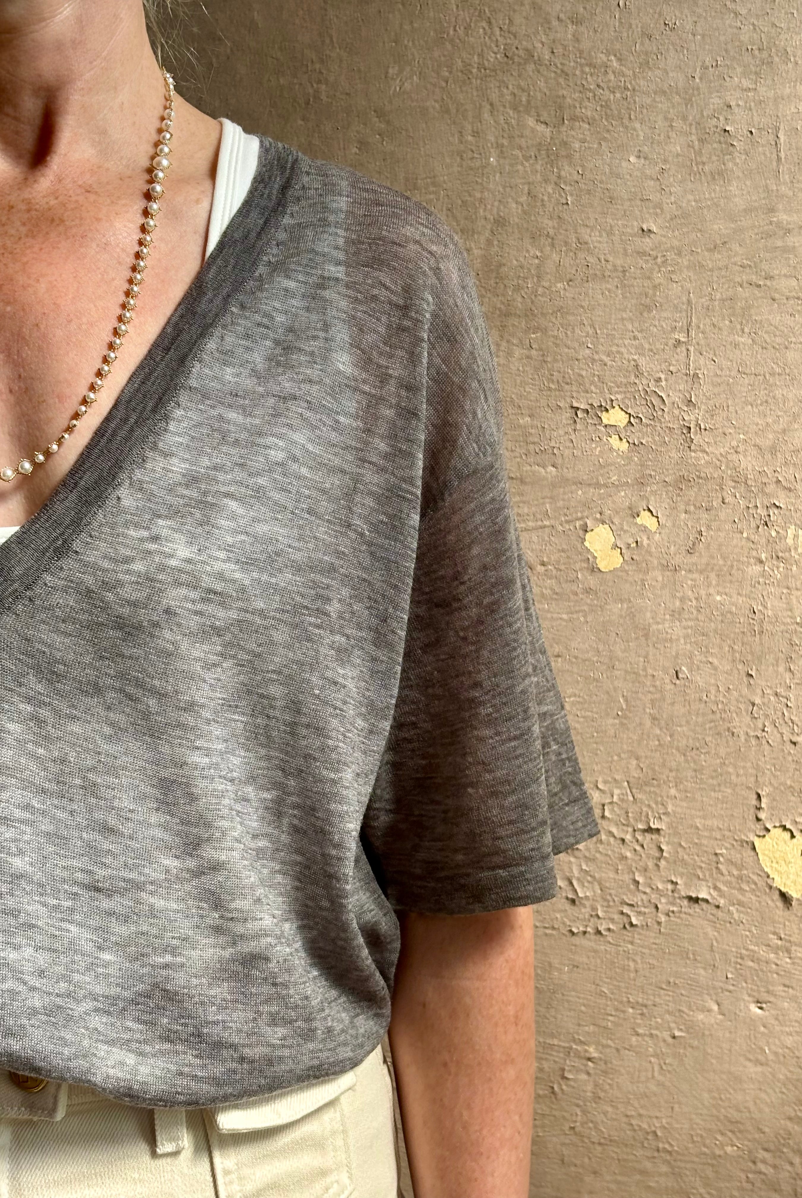 Mature woman wearing premium polished layer SPRWMN grey wool tee shirt with a v-neck and short sleeves