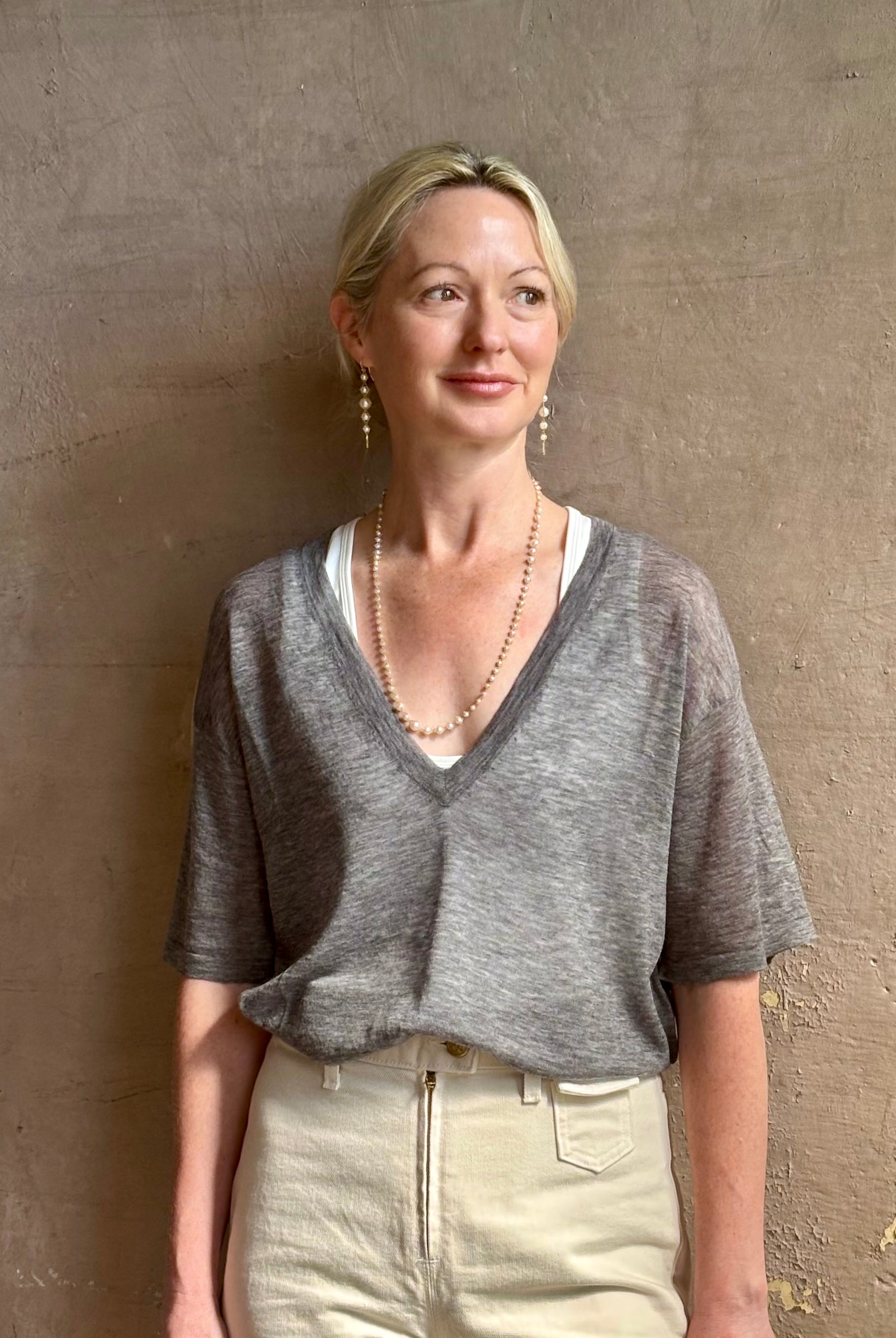 Mature woman wearing premium polished layer SPRWMN grey wool tee shirt with a v-neck and short sleeves