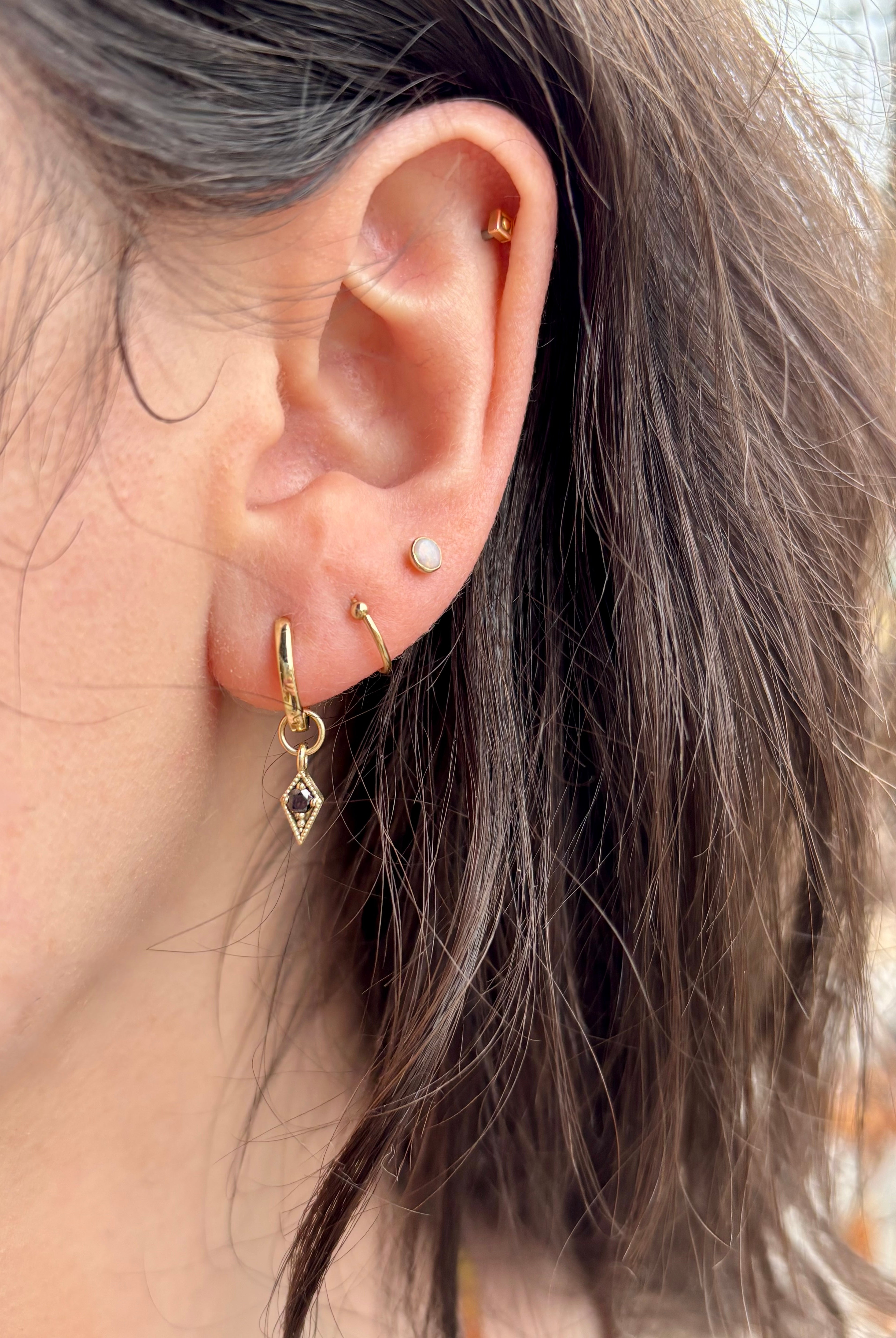 Woman wearing Asheville jeweler STEPHANIE ELLIS Black Diamond Charm Hoops in 14K Yellow Gold