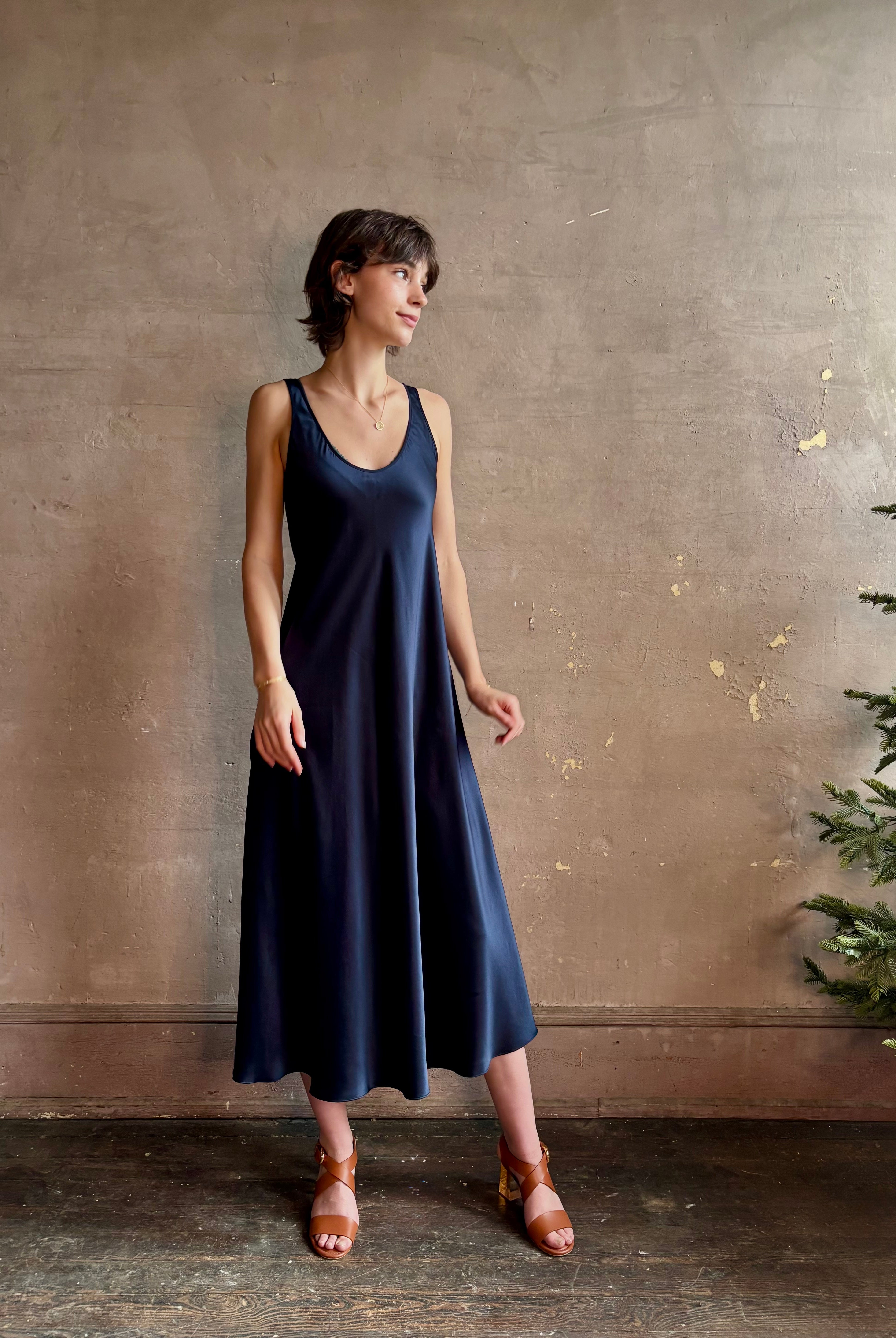 Womanl wearing luxury Sablyn navy blue silk charmeuse sleeveless slip maxi dress with scoop neck and low back