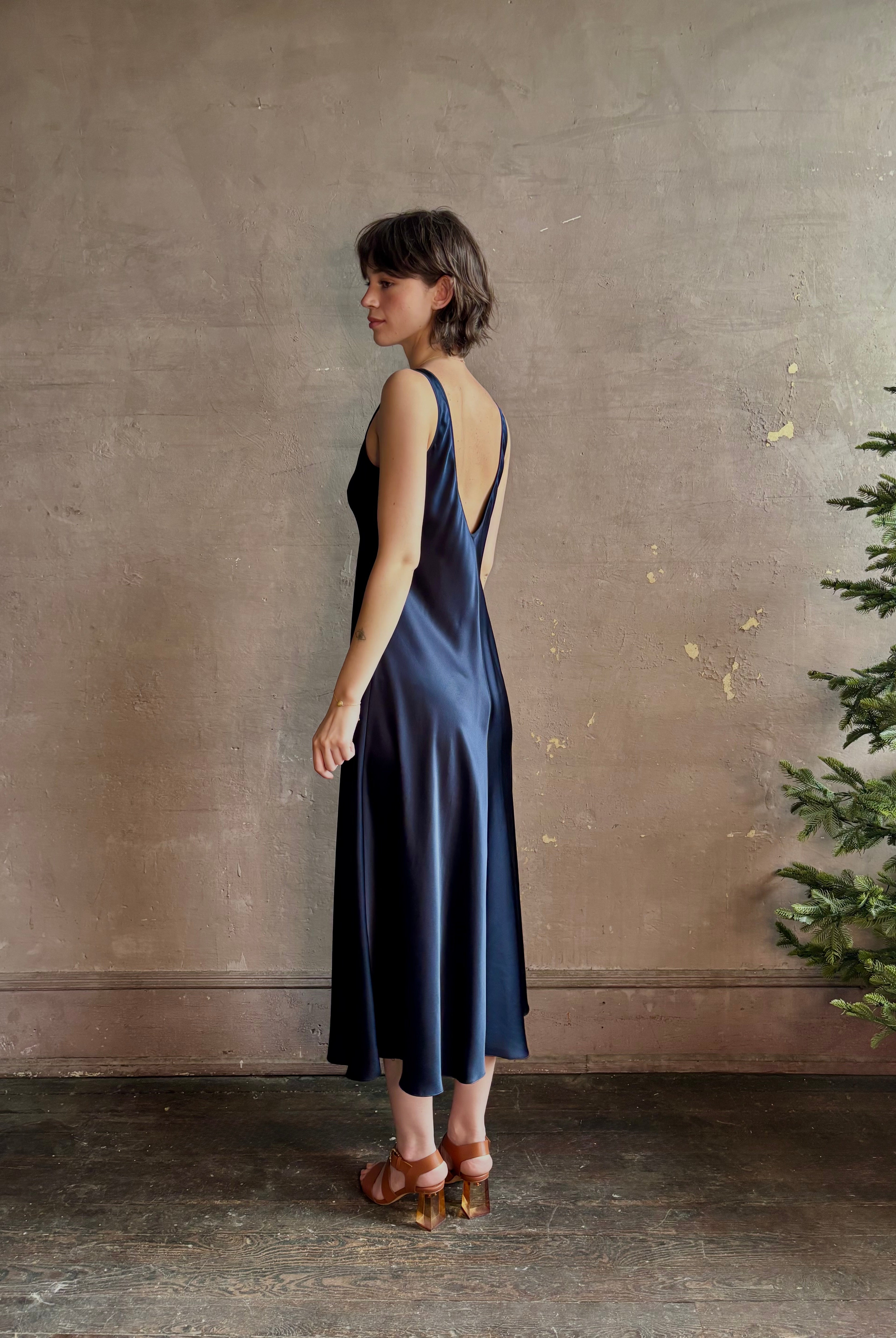 Womanl wearing luxury Sablyn navy blue silk charmeuse sleeveless slip maxi dress with scoop neck and low back