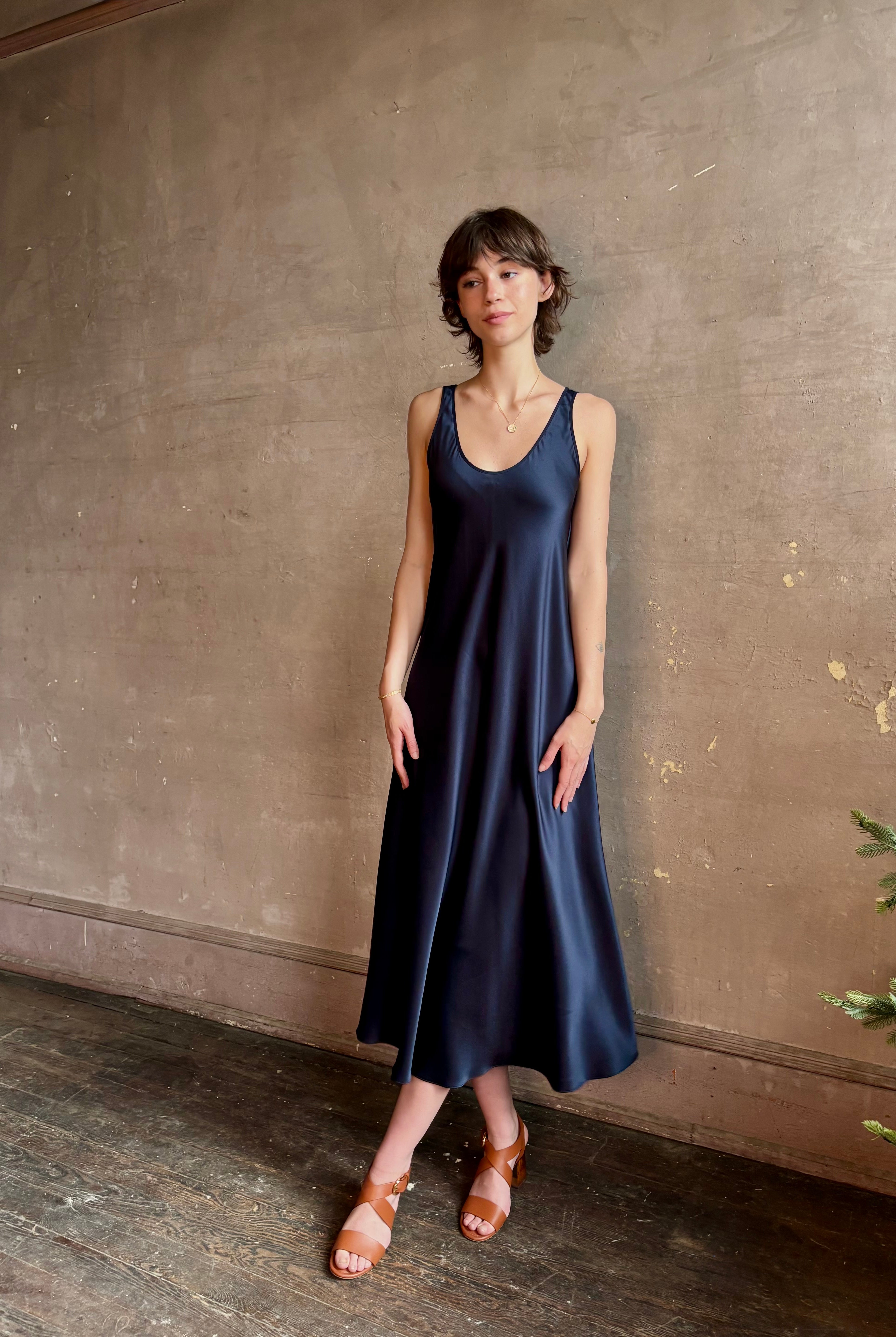 Womanl wearing luxury Sablyn navy blue silk charmeuse sleeveless slip maxi dress with scoop neck and low back