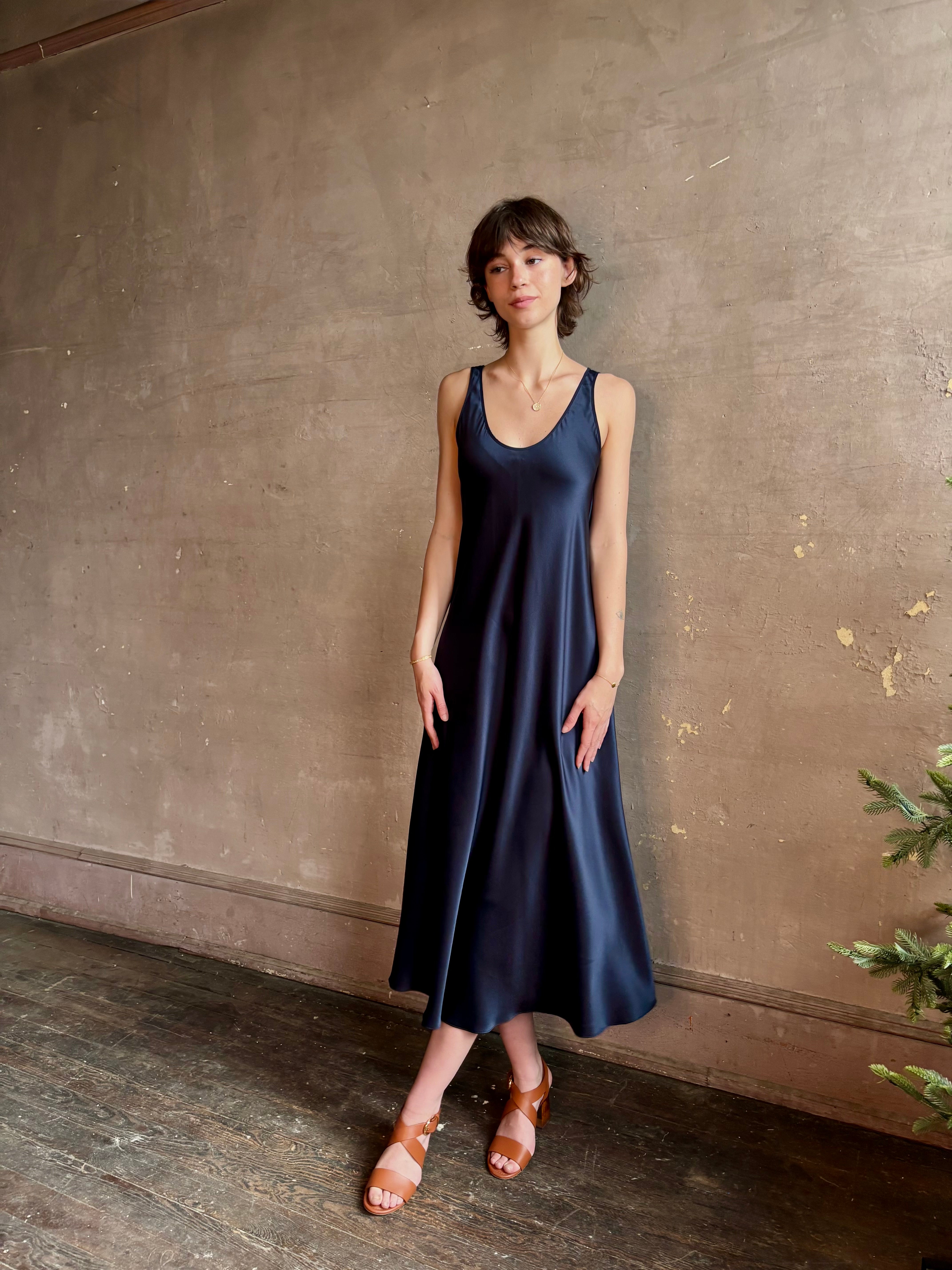 Womanl wearing luxury Sablyn navy blue silk charmeuse sleeveless slip maxi dress with scoop neck and low back