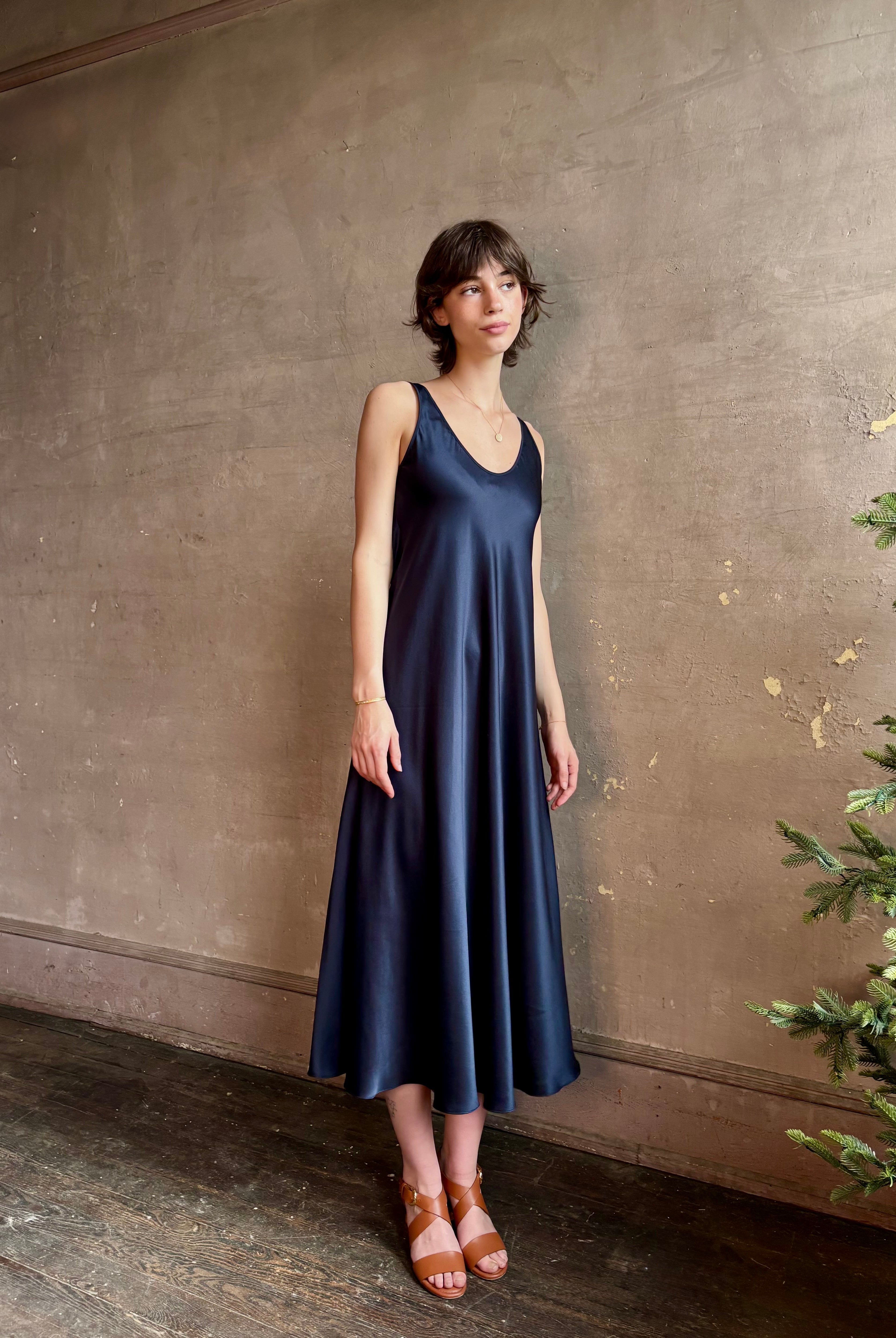 Womanl wearing luxury Sablyn navy blue silk charmeuse sleeveless slip maxi dress with scoop neck and low back