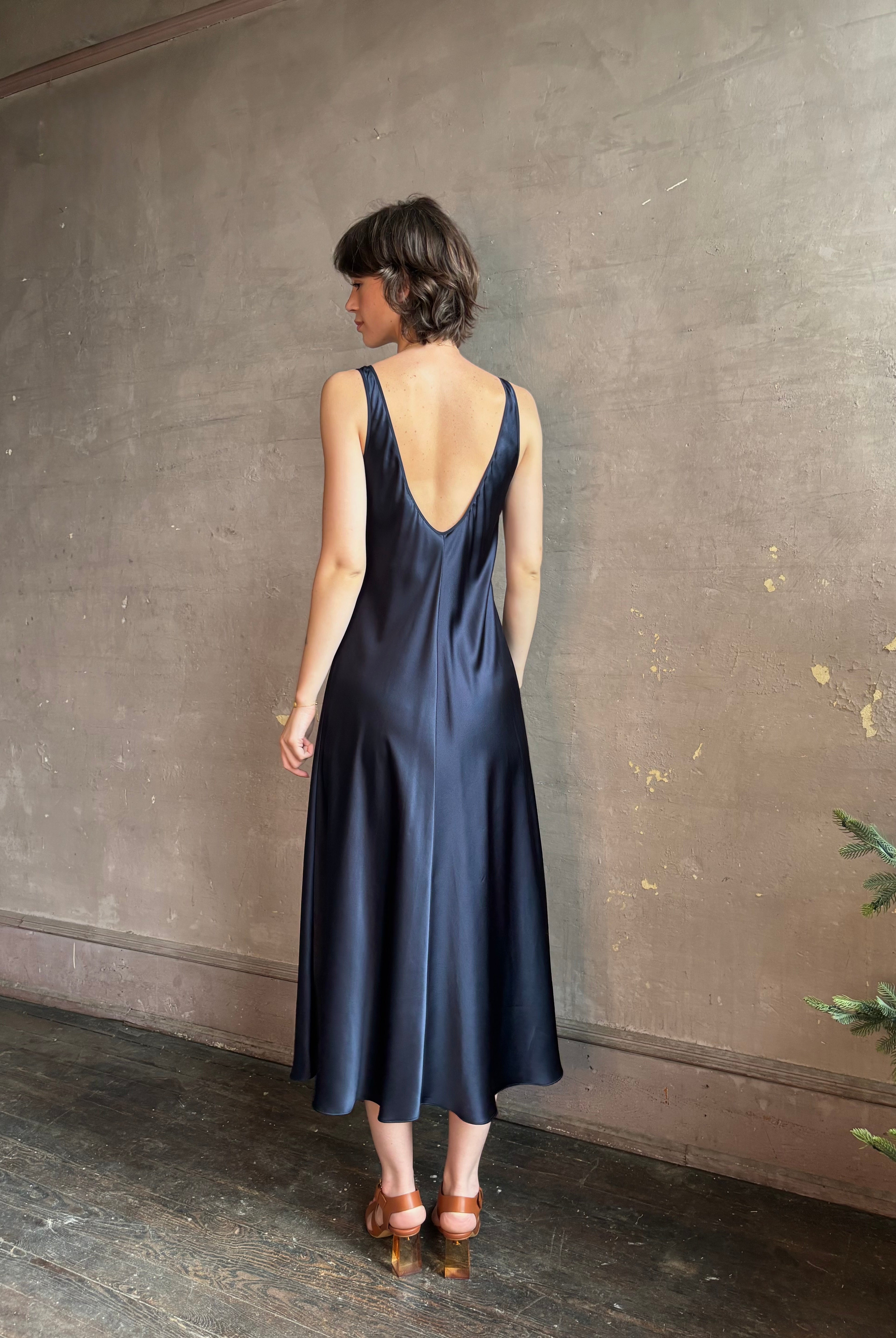 Womanl wearing luxury Sablyn navy blue silk charmeuse sleeveless slip maxi dress with scoop neck and low back