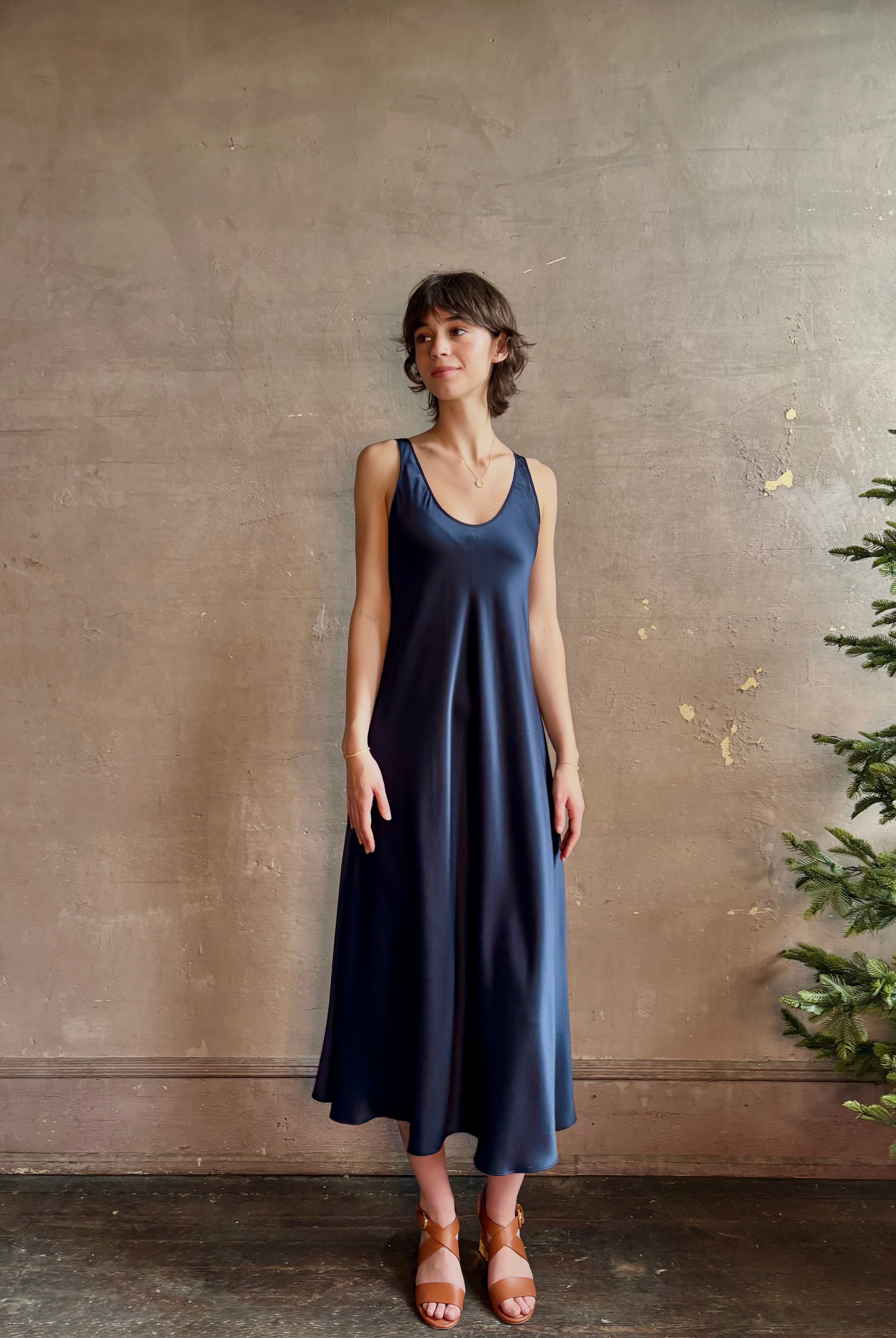 Womanl wearing luxury Sablyn navy blue silk charmeuse sleeveless slip maxi dress with scoop neck and low back