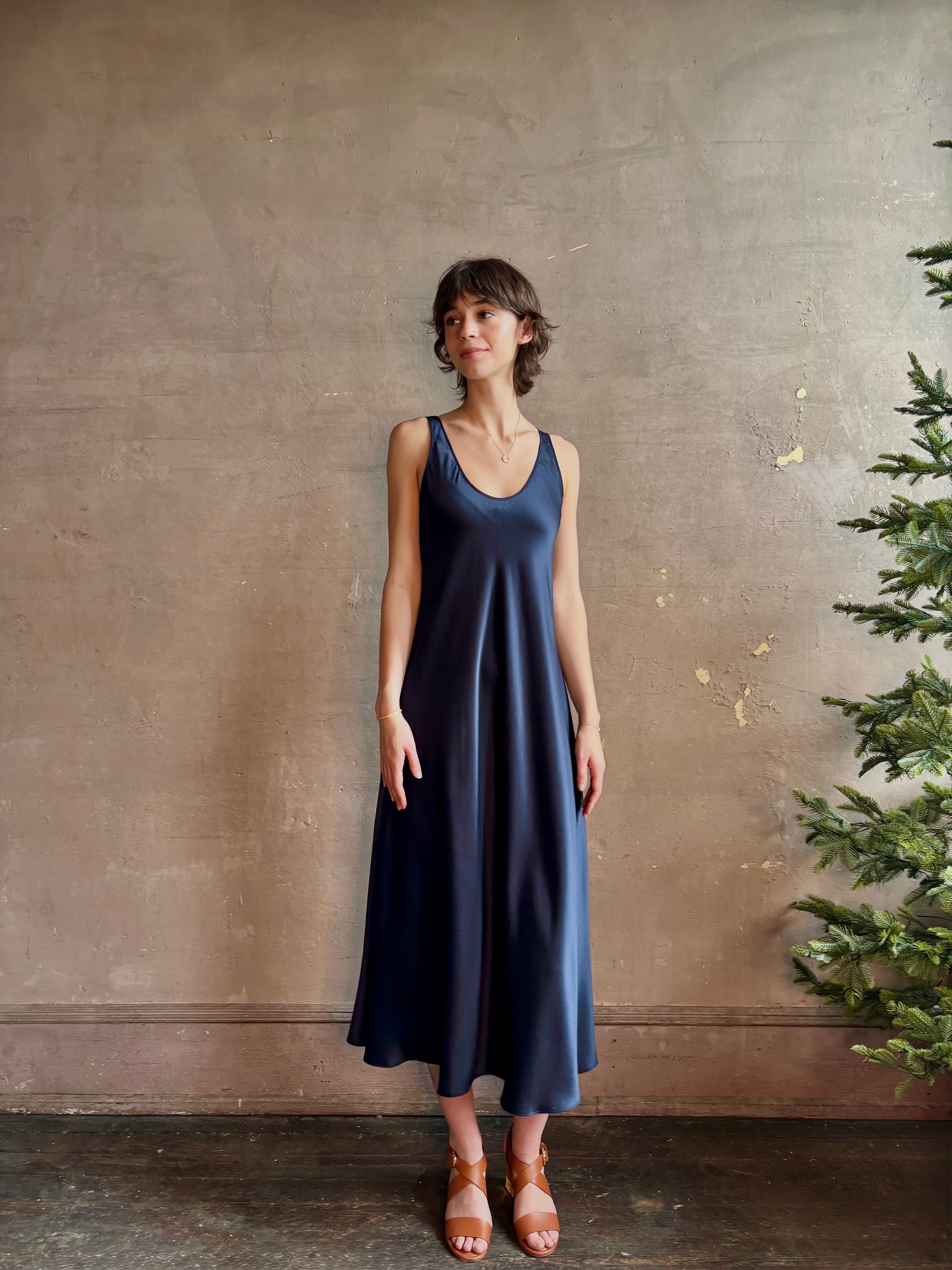 Womanl wearing luxury Sablyn navy blue silk charmeuse sleeveless slip maxi dress with scoop neck and low back