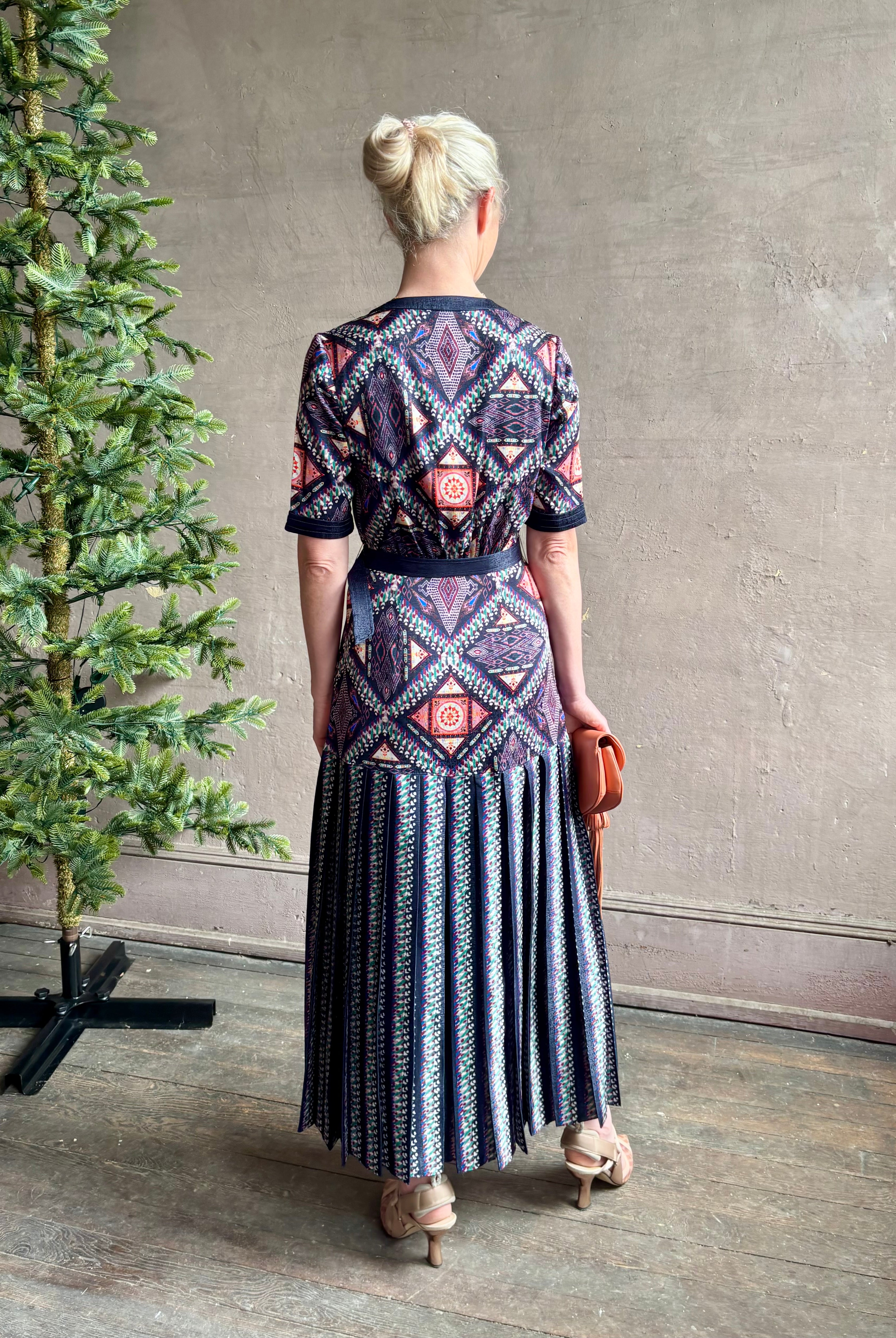 Mature woman wearing timeless Saloni Lea drop waist button front dress in ikat compass print and pleated skirt wit v-neck and short sleeves