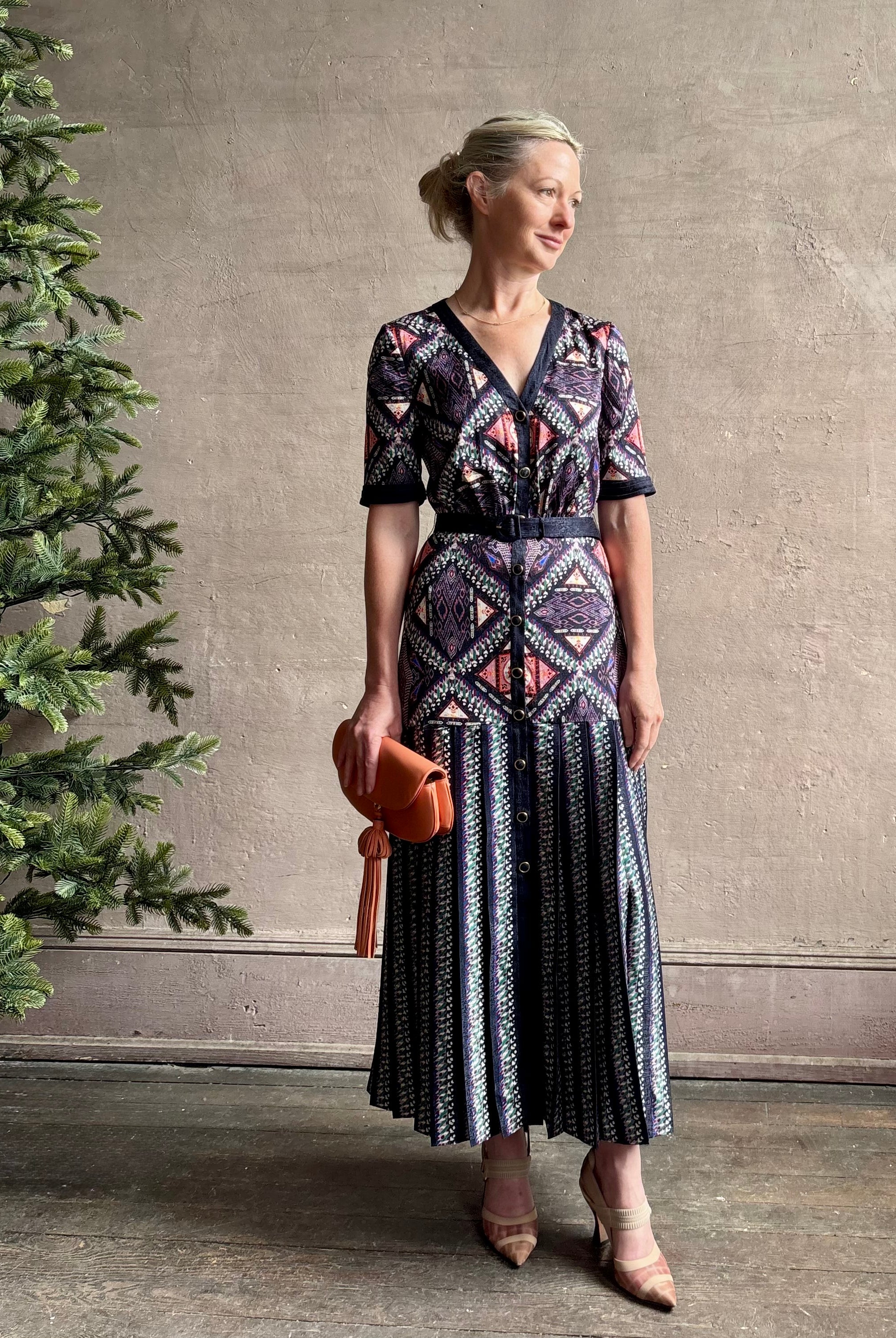 Mature woman wearing timeless Saloni Lea drop waist button front dress in ikat compass print and pleated skirt wit v-neck and short sleeves
