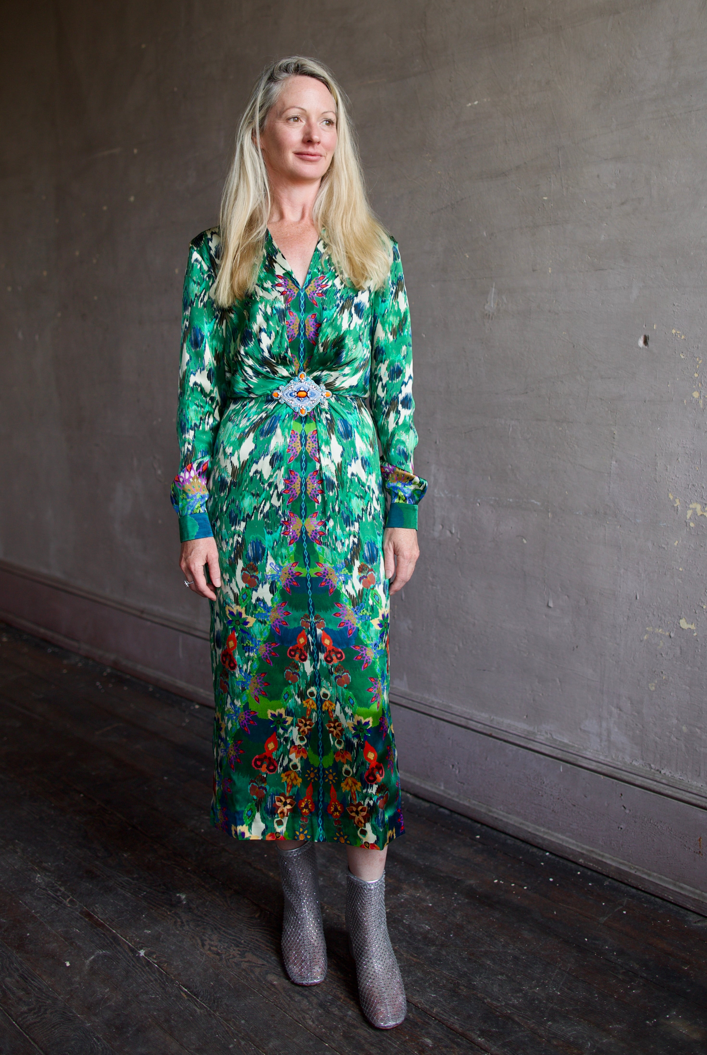Model wearing Saloni Mya silk long sleeve green floral midi dress with embellished broach detail at waist
