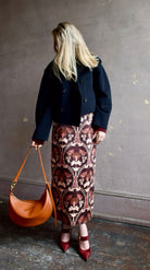 Image of woman wearing Cara Cara Blaze Skirt in Arcada Chocolate cotton-spandex construction with elegant Morris floral print, raffia belt, and straight hem