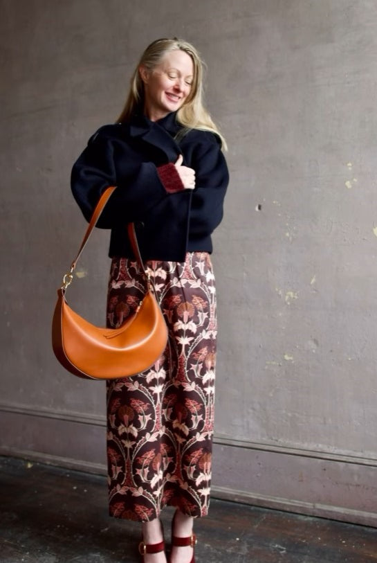Image of woman wearing Cara Cara Blaze Skirt in Arcada Chocolate cotton-spandex construction with elegant Morris floral print, raffia belt, and straight hem
