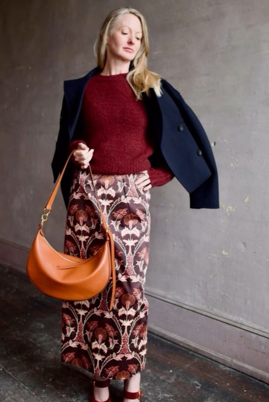 Image of woman wearing Cara Cara Blaze Skirt in Arcada Chocolate cotton-spandex construction with elegant Morris floral print, raffia belt, and straight hem