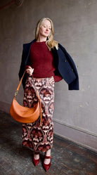 Image of woman wearing Cara Cara Blaze Skirt in Arcada Chocolate cotton-spandex construction with elegant Morris floral print, raffia belt, and straight hem