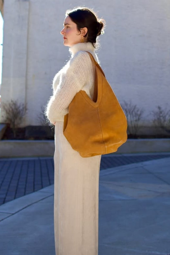 Model wearing luxury Italian leather large hobo by designer Mansur Gavriel  with v-detail handle in camel color