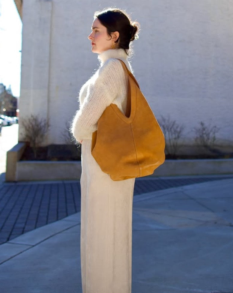 Model wearing luxury Italian leather large hobo by designer Mansur Gavriel with v-detail handle in camel color