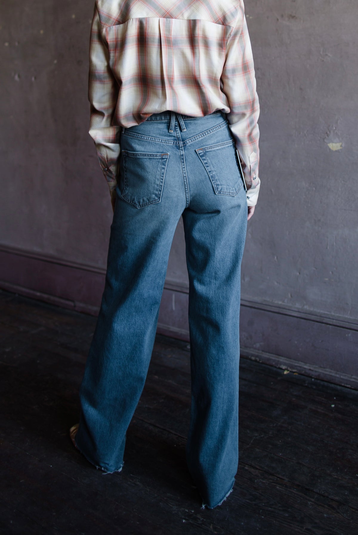 Mature woman wearing Slvrlake Grace denim jeans in 100% cotton rigid denim high rise full length wide leg medium wash