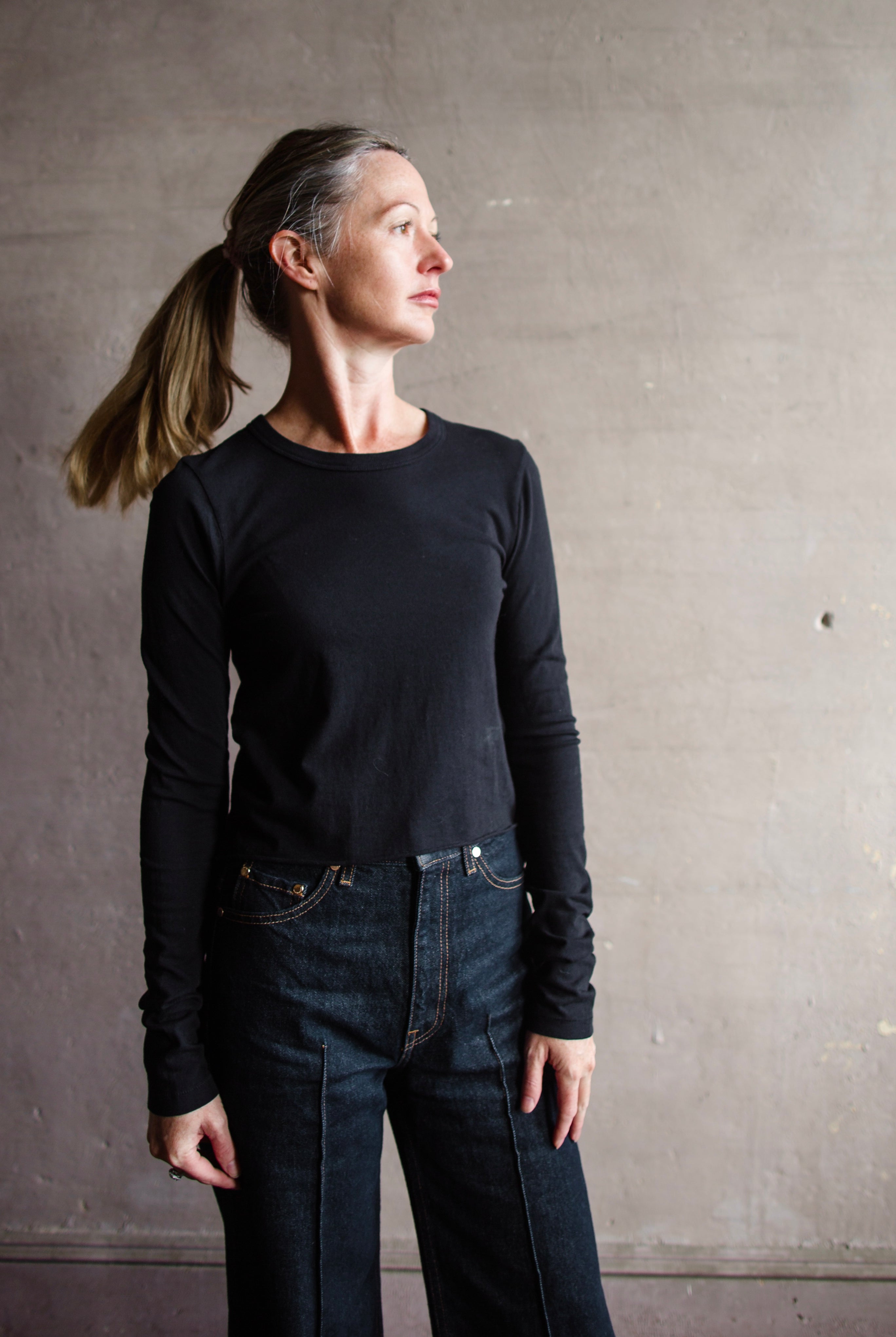 Image featuring a woman wearing the Slvrlake The Baby Long Sleeve Tee by Slvrlake baby tee with a crew neckline, long sleeves and a cropped fit fabricated in cotton.