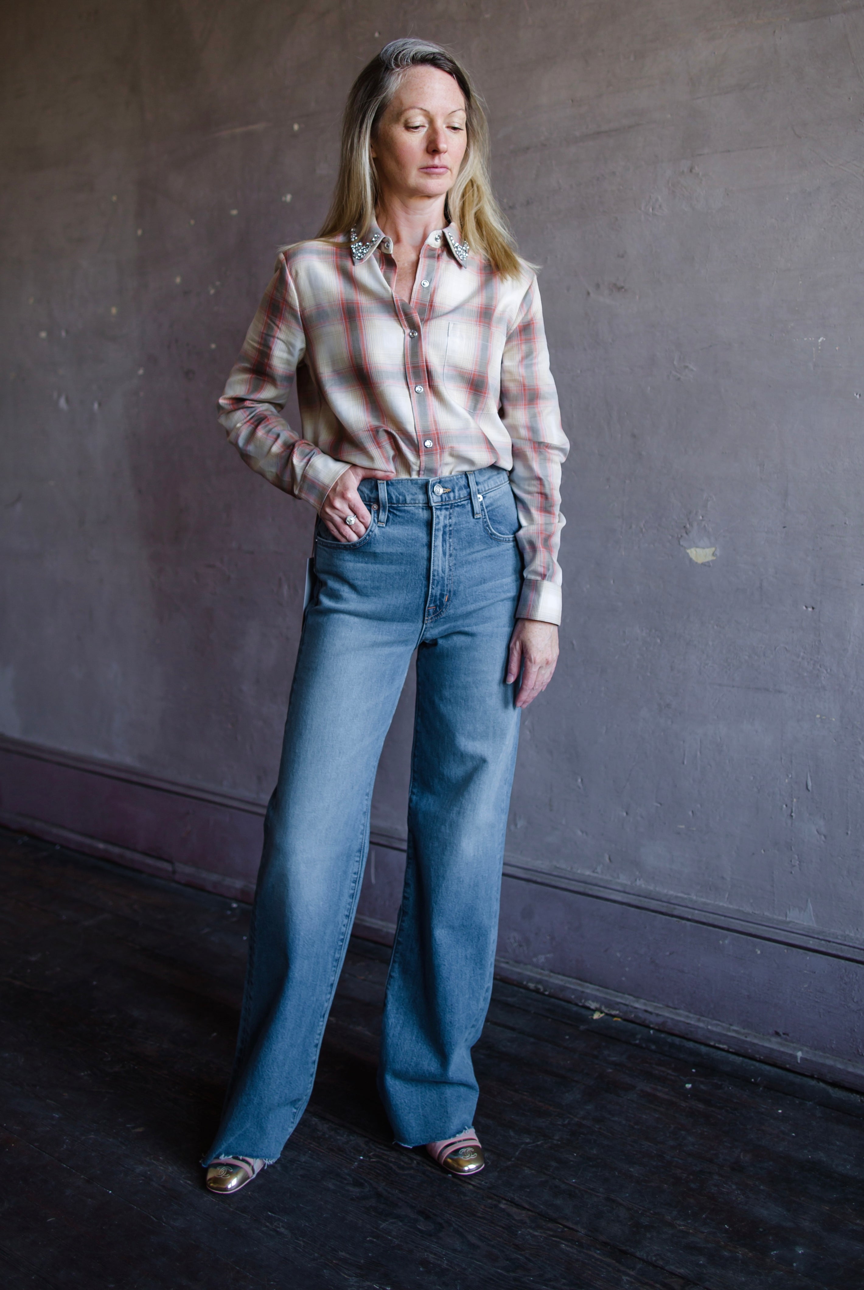 Mature woman wearing Slvrlake Grace denim jeans in 100% cotton rigid denim high rise full length wide leg medium wash