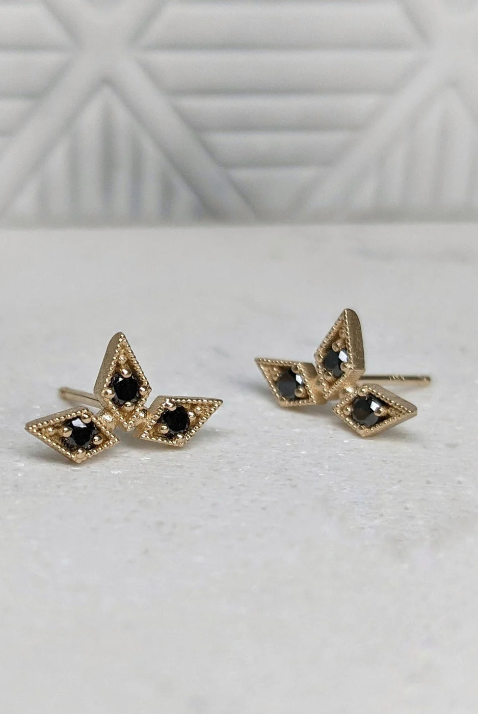 Image of luxury fine jewelry designer Stephanie Ellis triple star stud earrings with 14 carat yellow gold and ethically sourced black diamonds