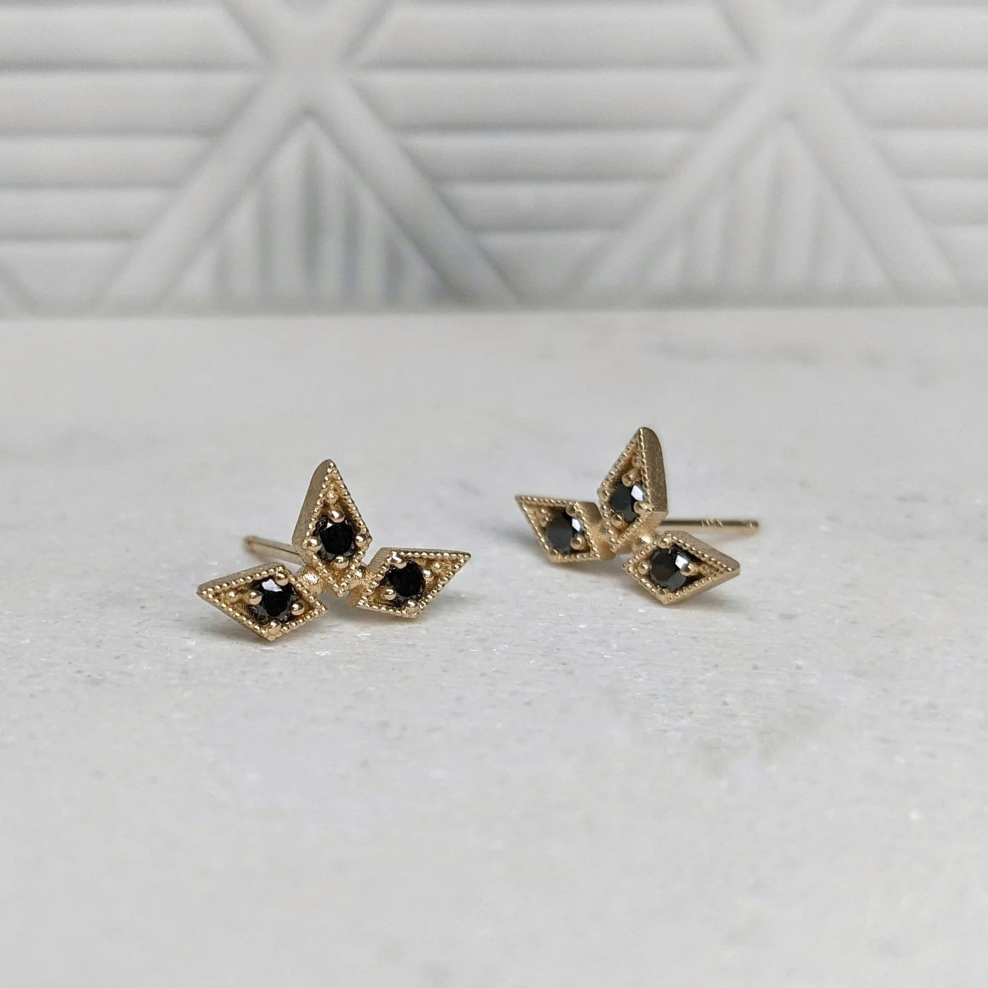 Image of luxury fine jewelry designer Stephanie Ellis triple star stud earrings with 14 carat yellow gold and ethically sourced black diamonds