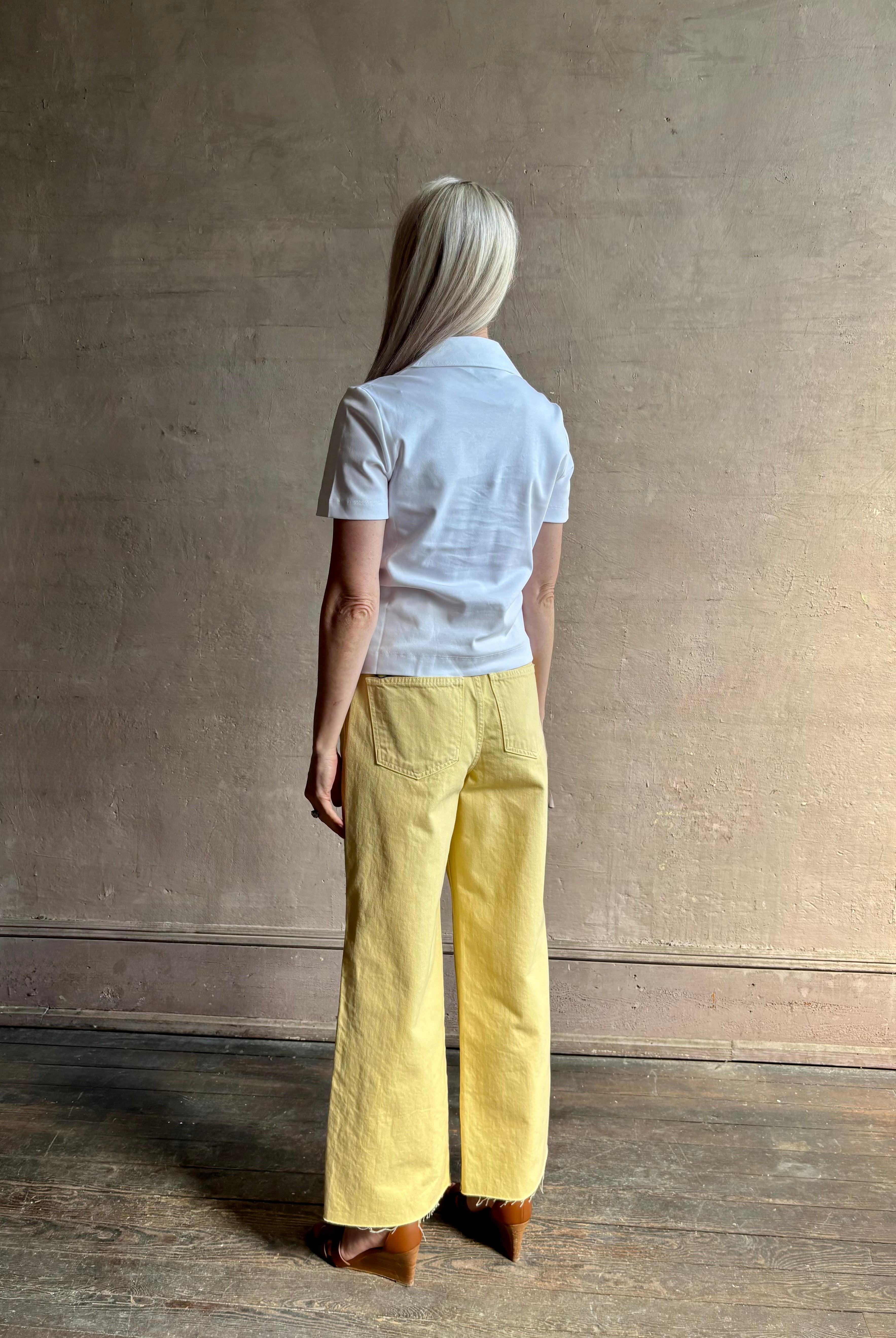 Mature woman wearing timeless white Melanie Top from Tanya Taylor crafted from 100% organic cotton jersey with v-neck and short sleeves in effortless relaxed fit for an elevated waredrobe staple