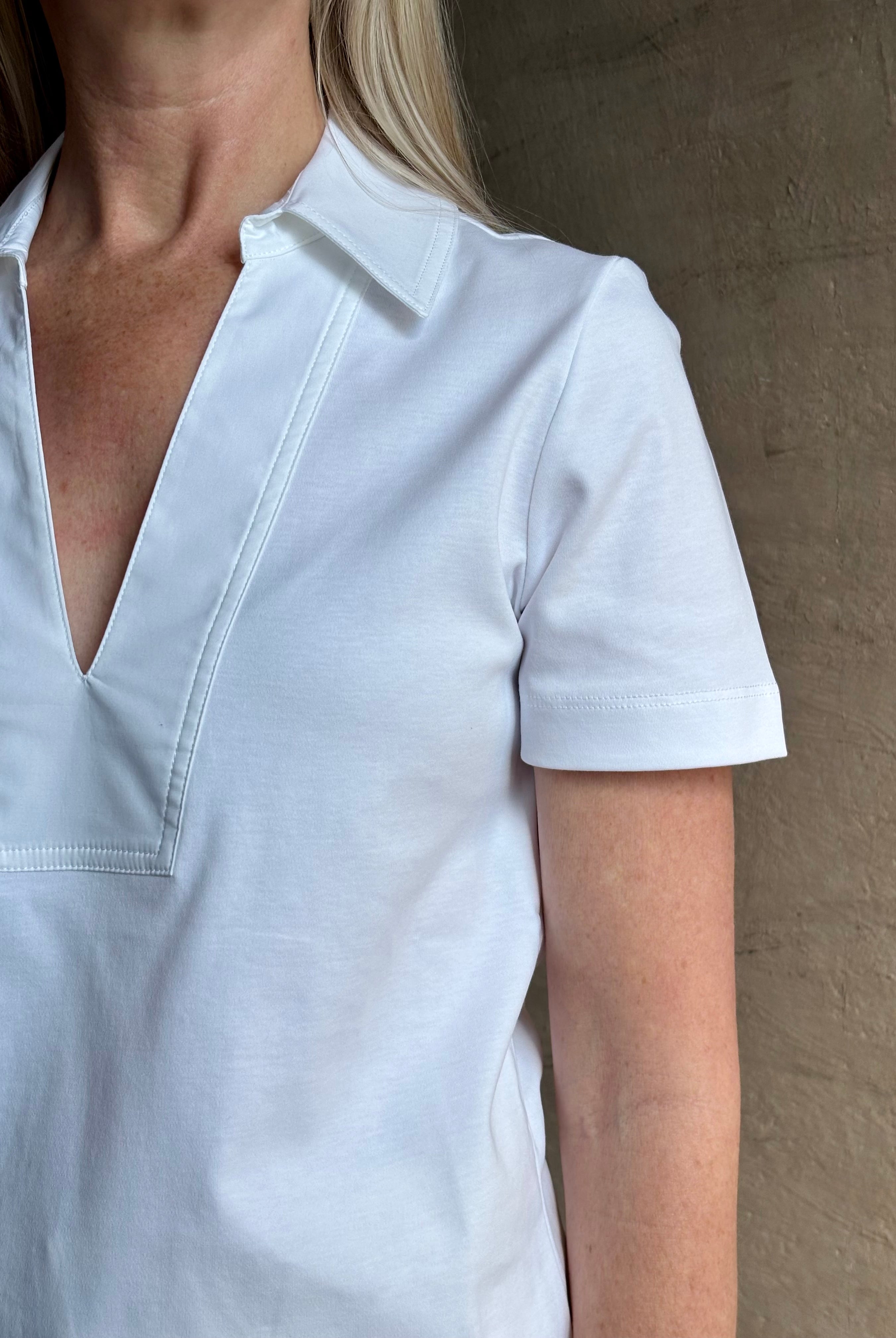 Mature woman wearing timeless white Melanie Top from Tanya Taylor crafted from 100% organic cotton jersey with v-neck and short sleeves in effortless relaxed fit for an elevated waredrobe staple