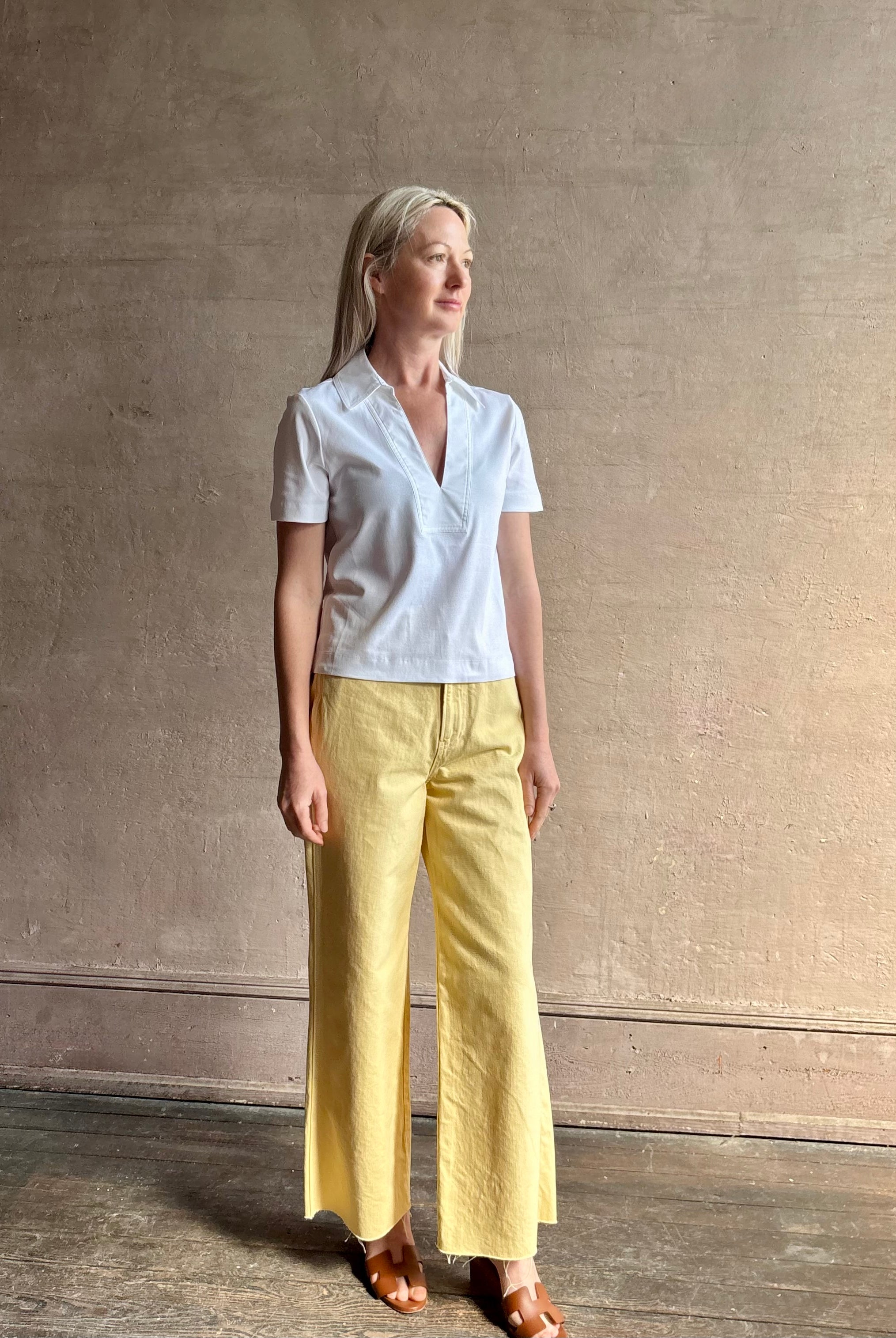 Mature woman wearing timeless white Melanie Top from Tanya Taylor crafted from 100% organic cotton jersey with v-neck and short sleeves in effortless relaxed fit for an elevated waredrobe staple