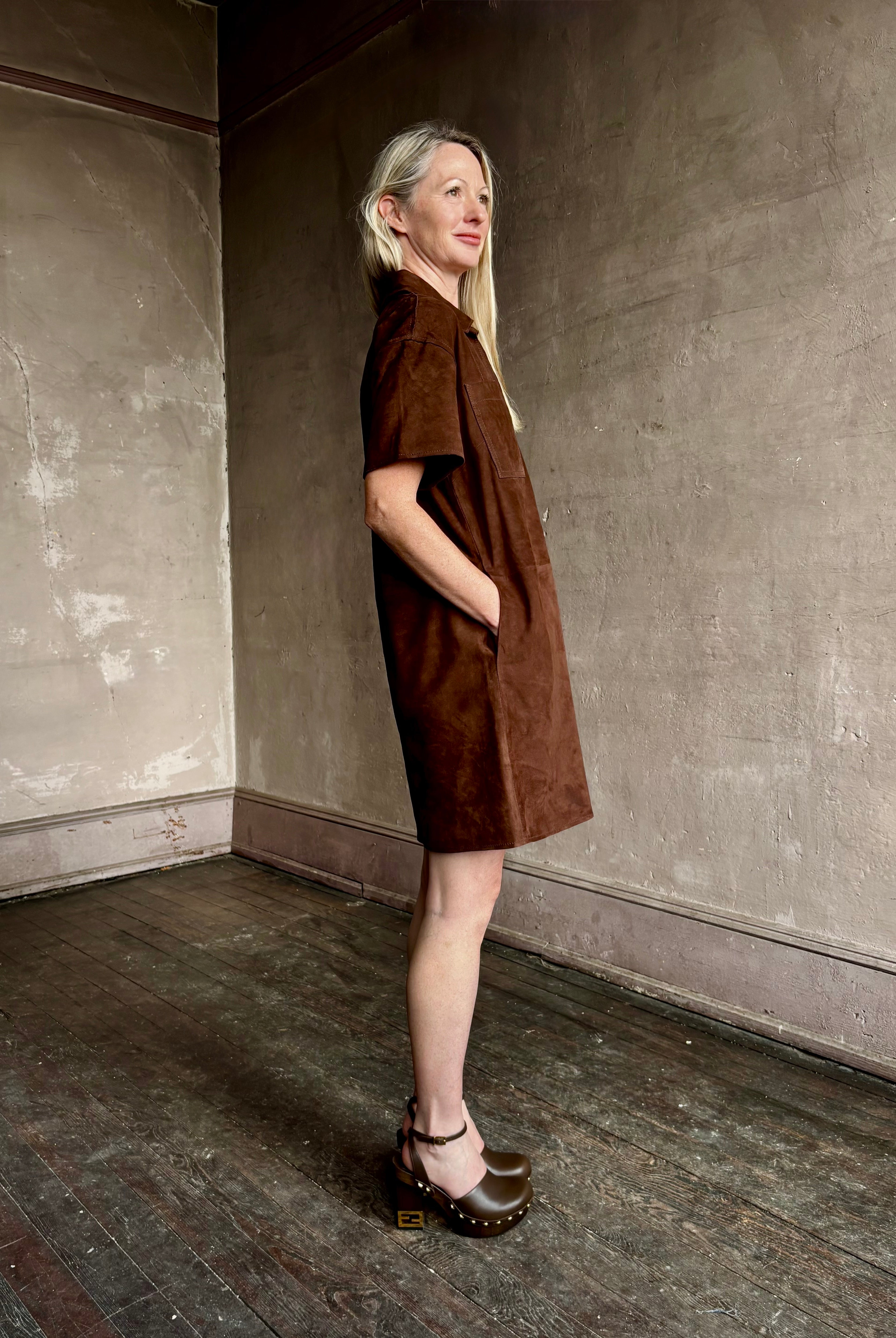 Image of mature woman wearing designer Tanya Taylor sleek chocolate leather shift dress with V-neck and structured collar