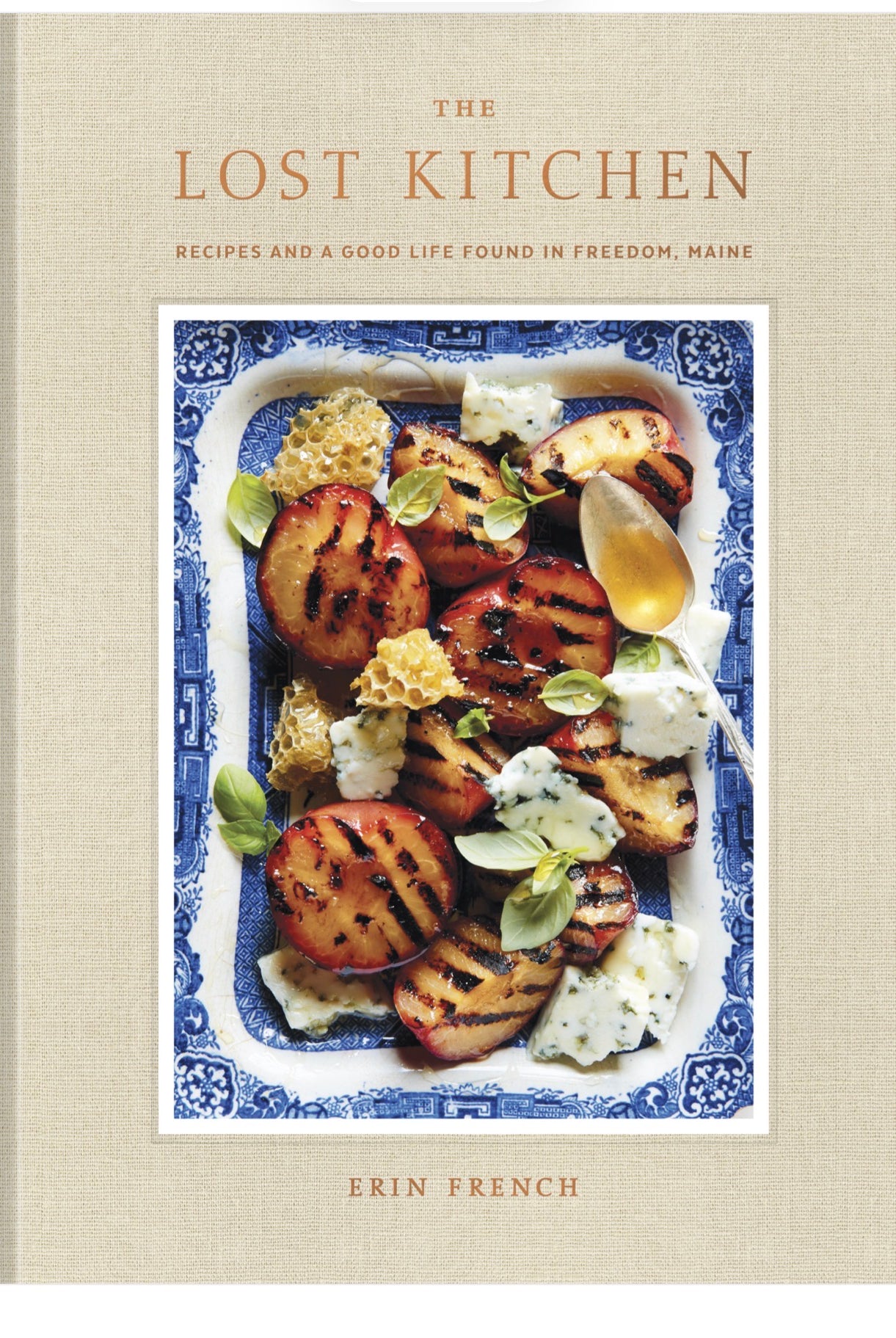 The Lost Kitchen cookbook cover by Erin French, featuring grilled peaches and cheese dish on a blue-and-white plate