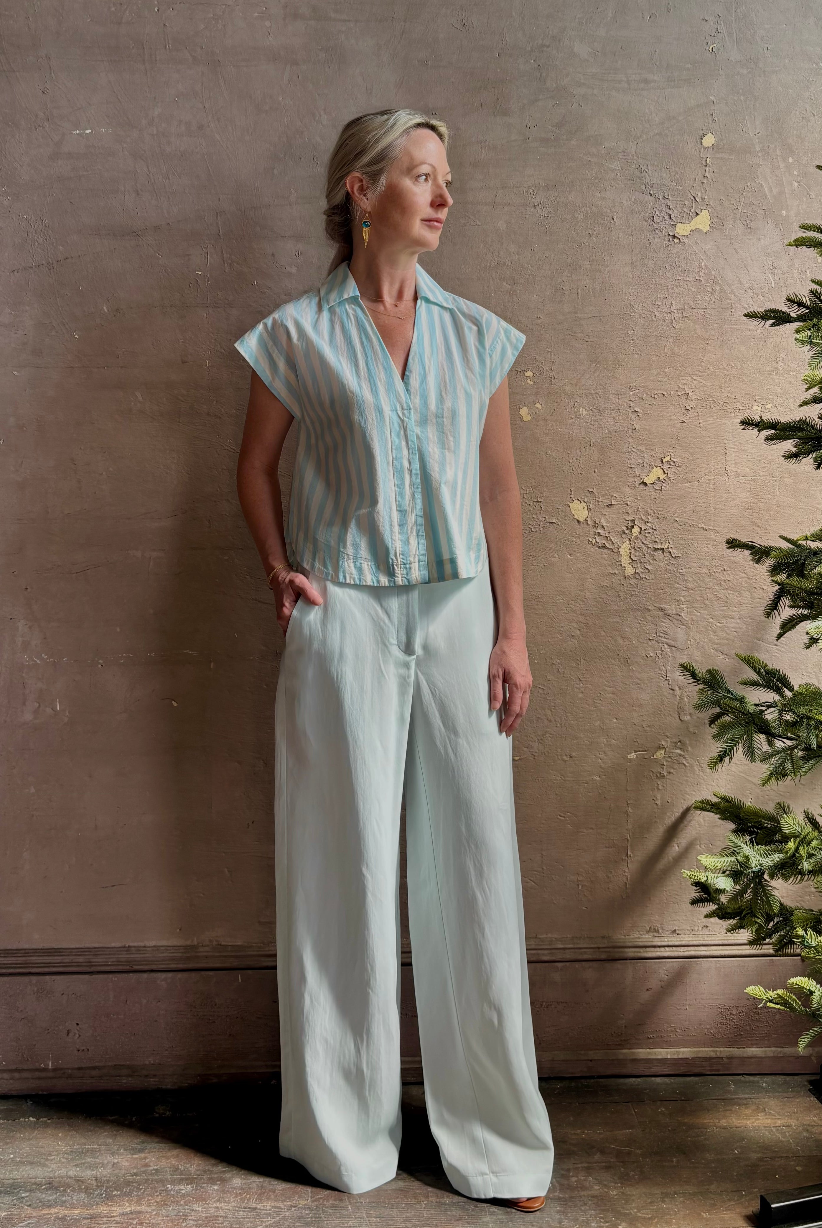 Mature woman wearing Dorada short sleeve Shirt from Trovata rendered in a fresh aqua and cream Stripe and crafted from cotton poplin with v-neck, collar and consealed button front