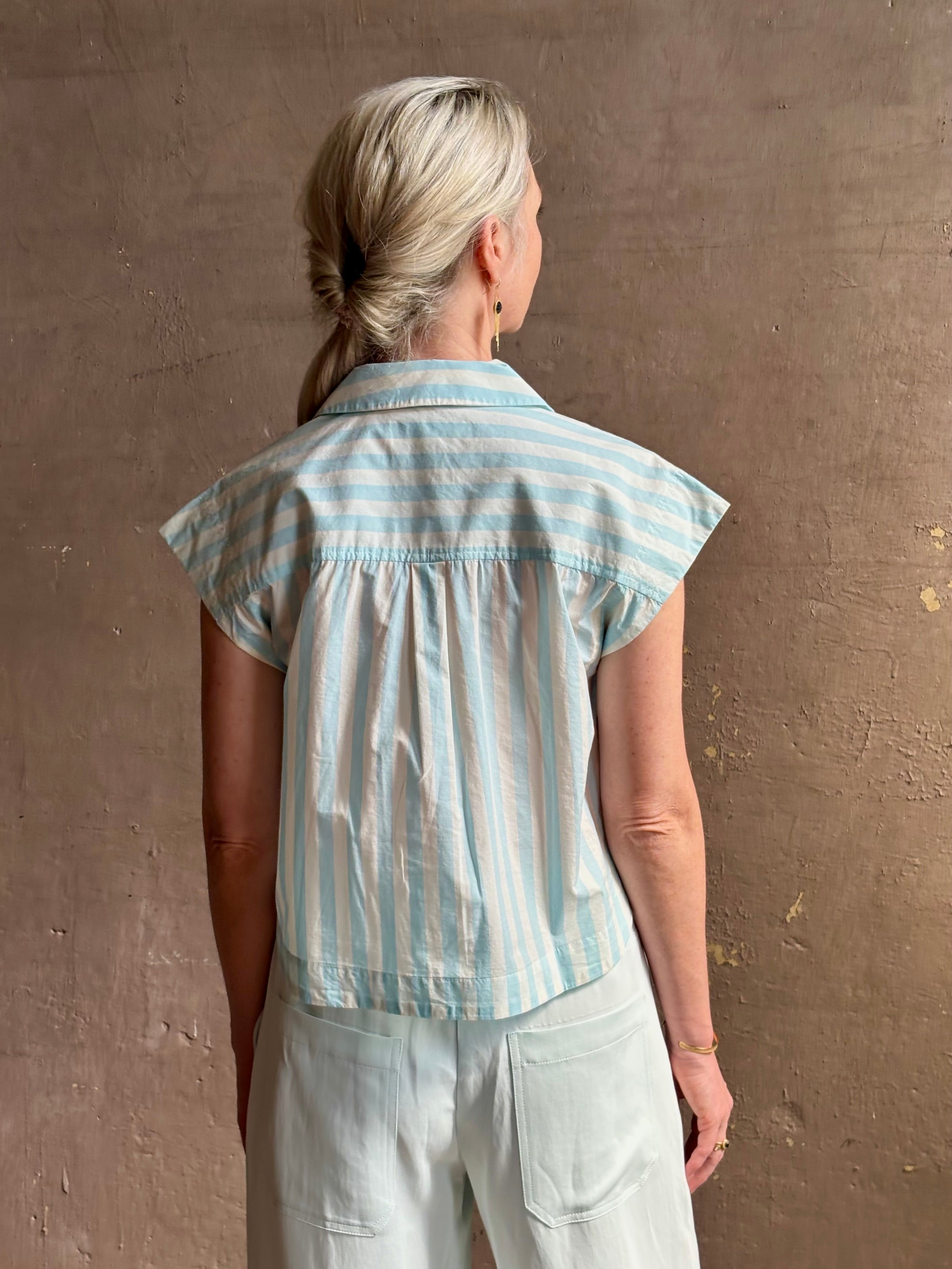 Mature woman wearing Dorada short sleeve Shirt from Trovata rendered in a fresh aqua and cream Stripe and crafted from cotton poplin with v-neck, collar and consealed button front