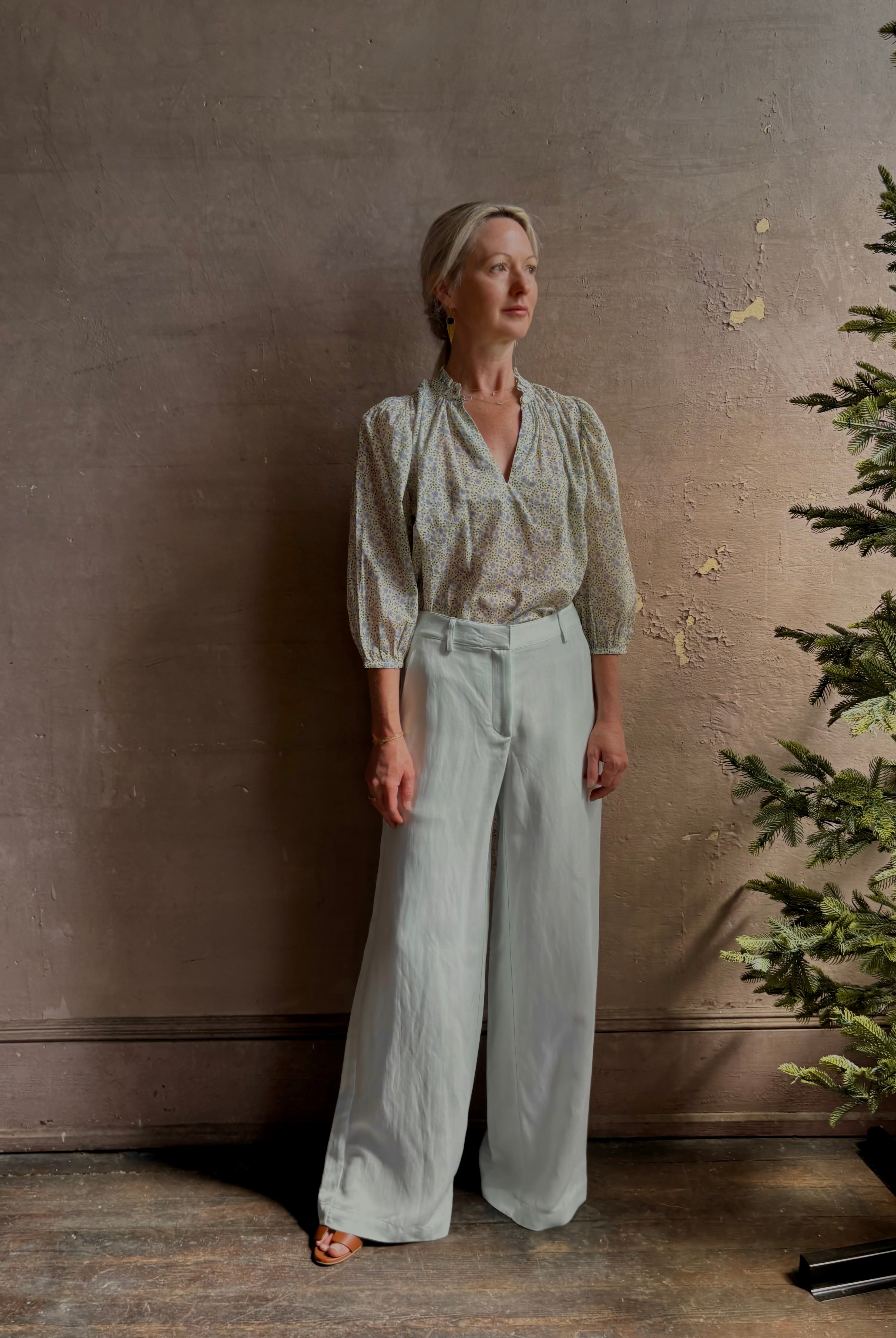 Mature woman wearing the Orly blouse from Trovata rendered in a charming coastal inspired floral print and crafted from cotton with three quarter sleeves and ruffle lined v-neck