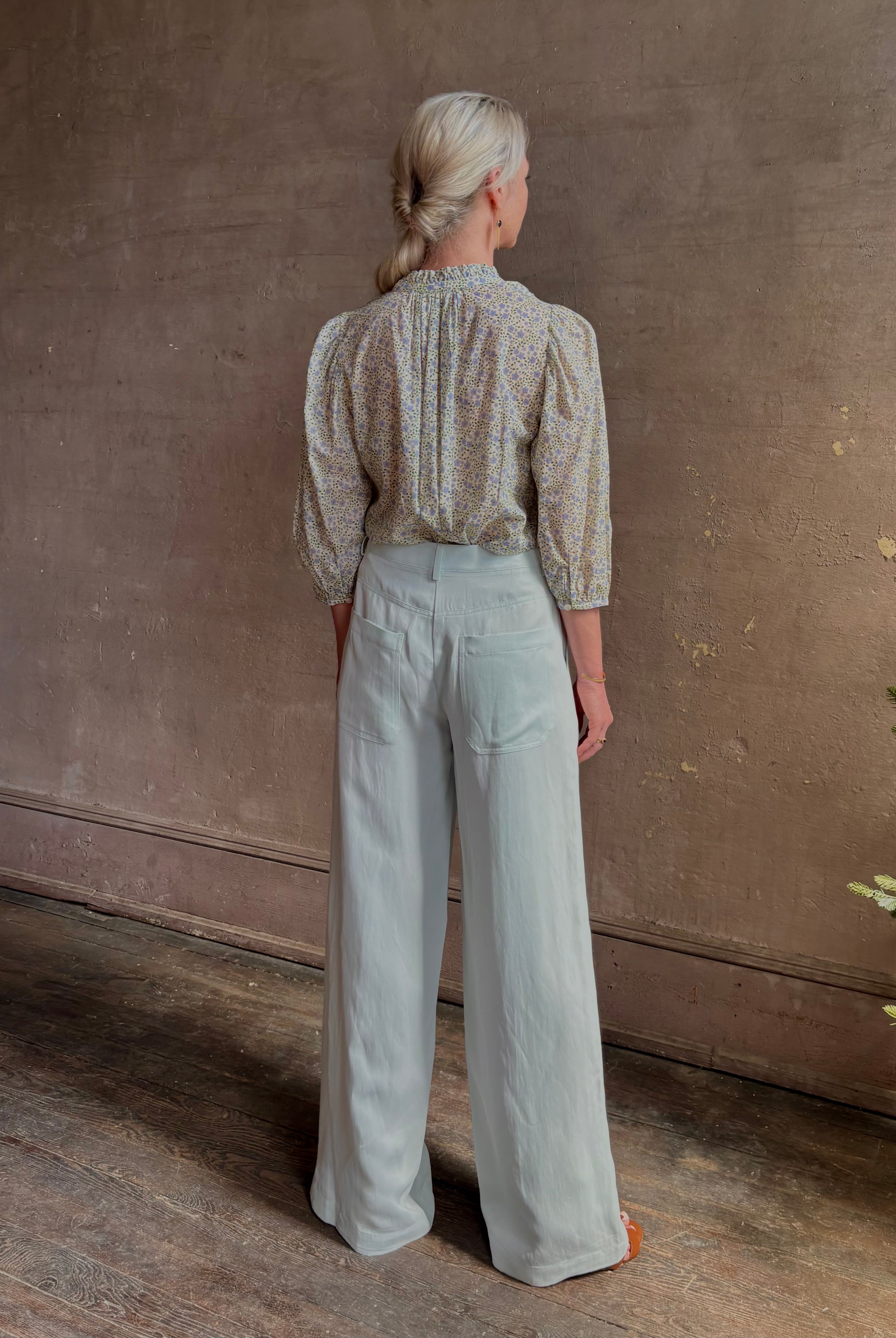 Mature woman wearing the Orly blouse from Trovata rendered in a charming coastal inspired floral print and crafted from cotton with three quarter sleeves and ruffle lined v-neck